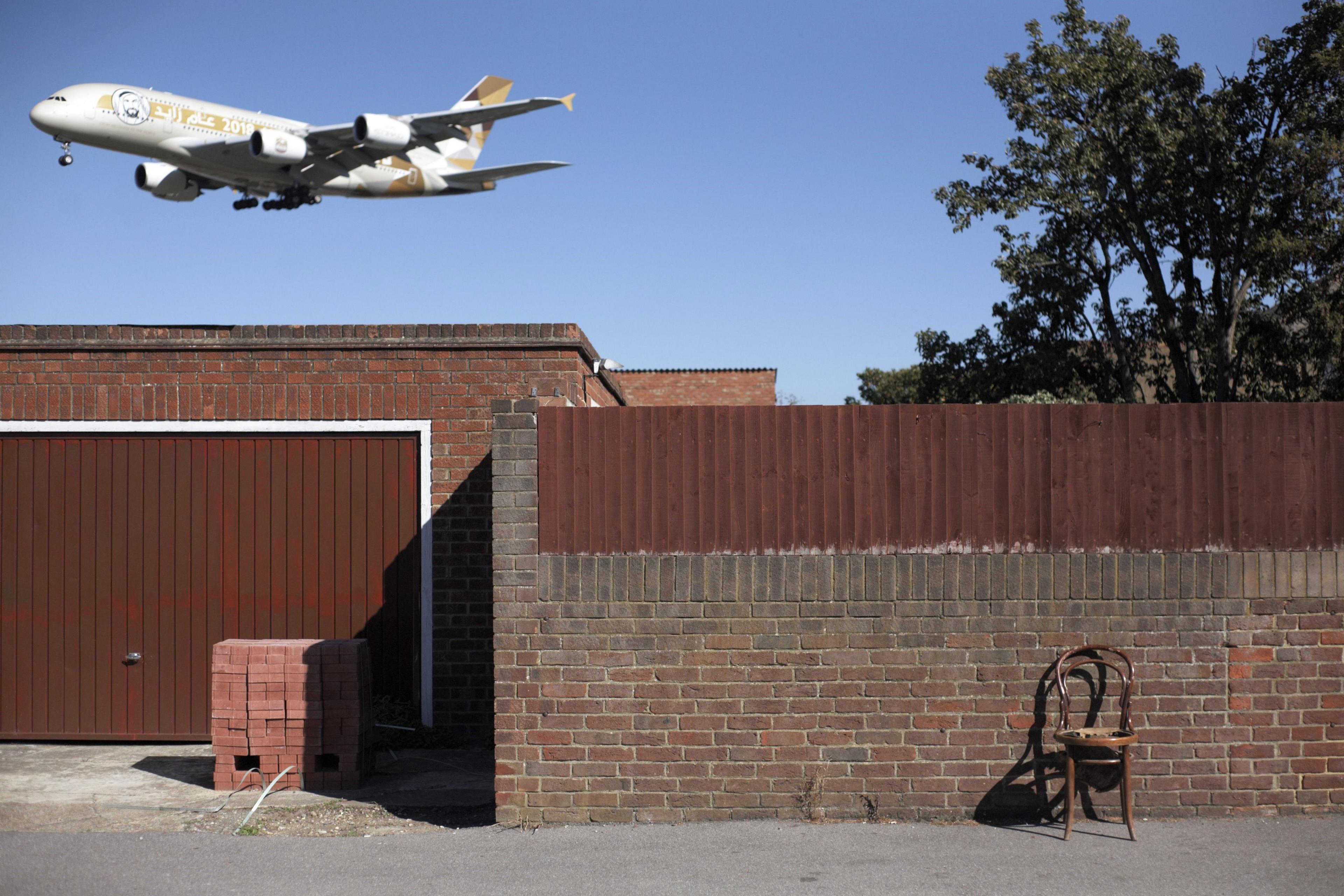 Chair by brick wall beneath aeroplane