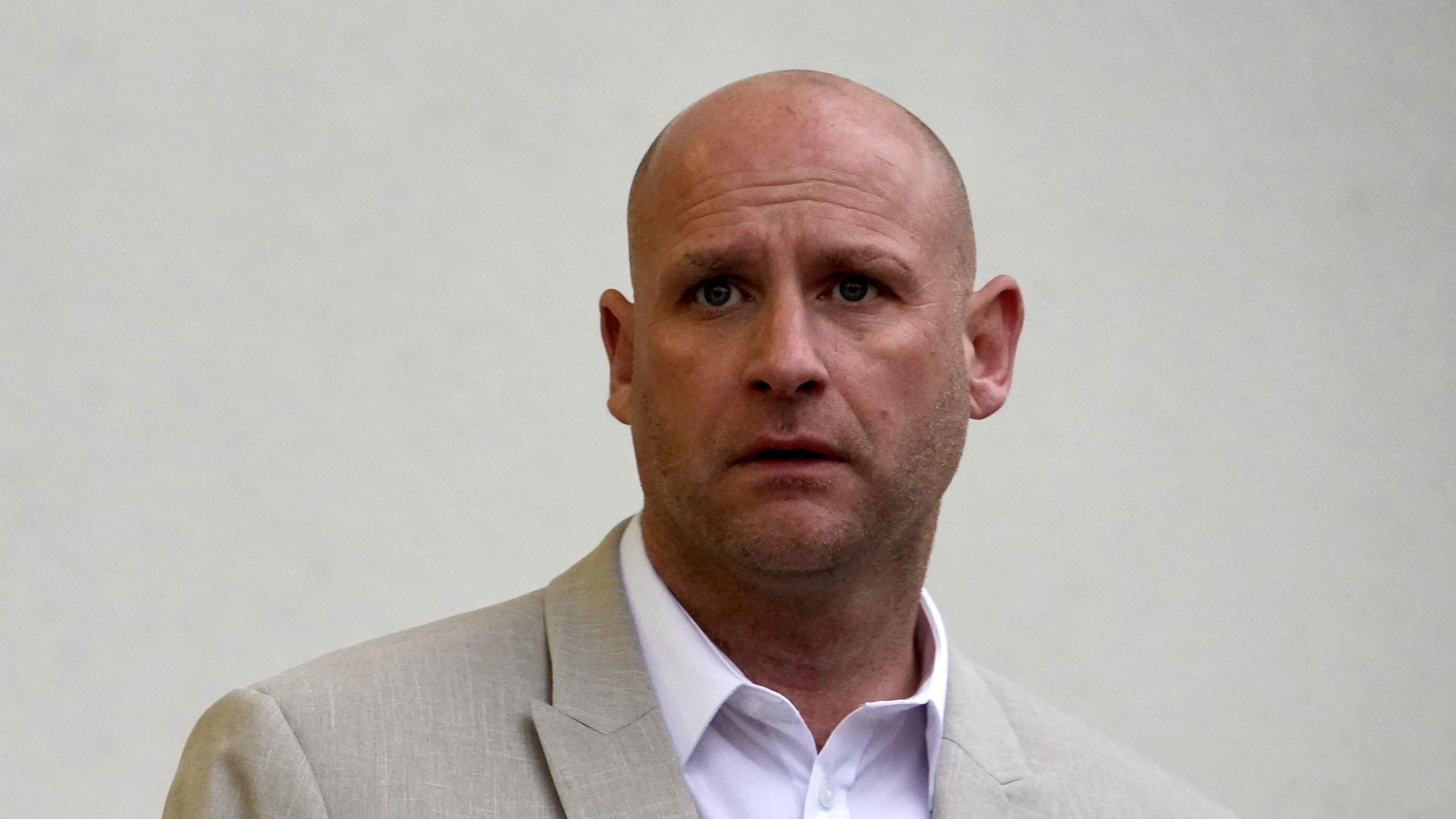 A close-up image of Grant Phillips wearing a cream blazer over a light coloured smart shirt. He is looking towards the camera.