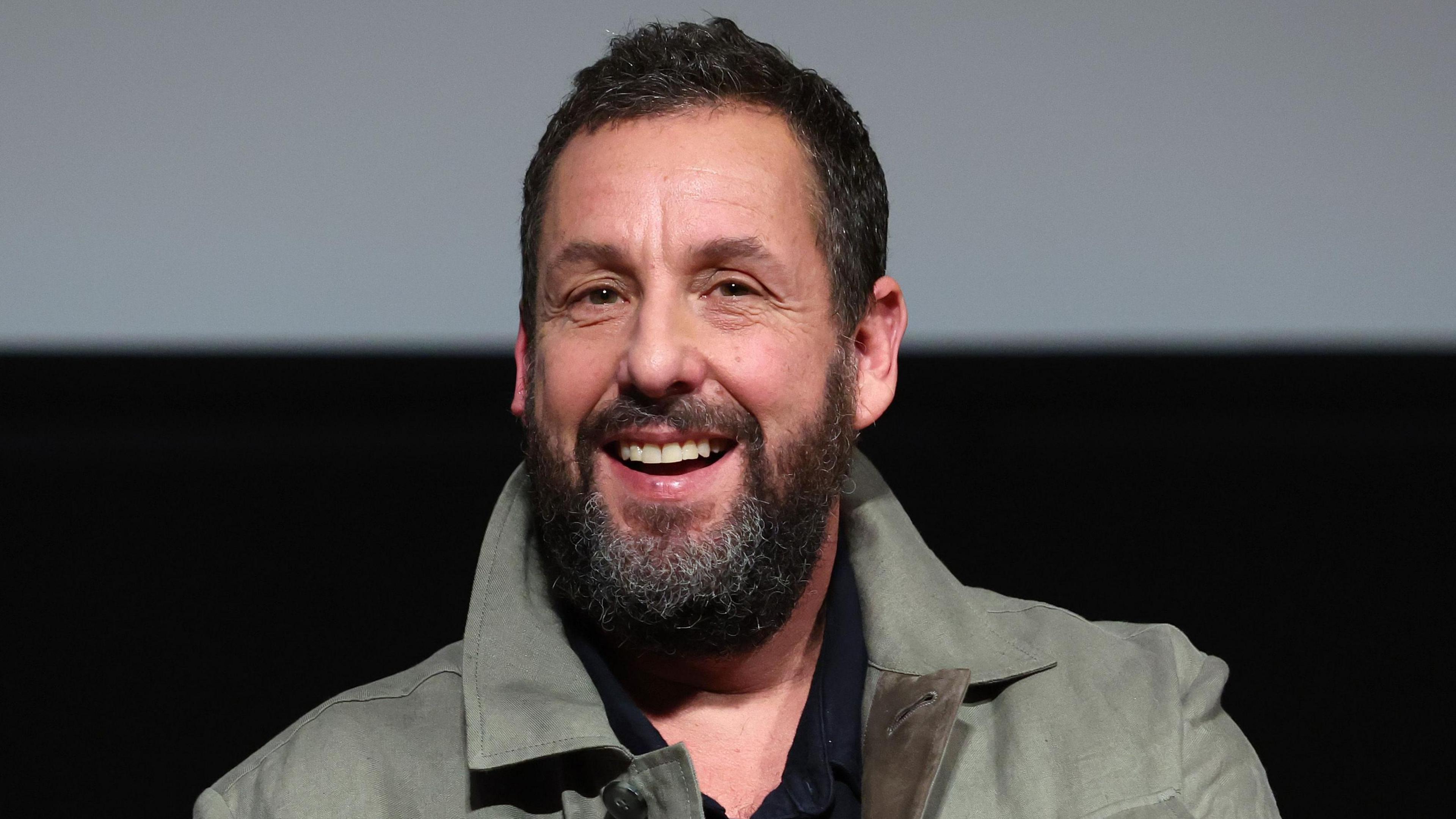 Adam Sandler smiling on stage during a Jay Kelly Bafta screening in Los Angeles in November 2025