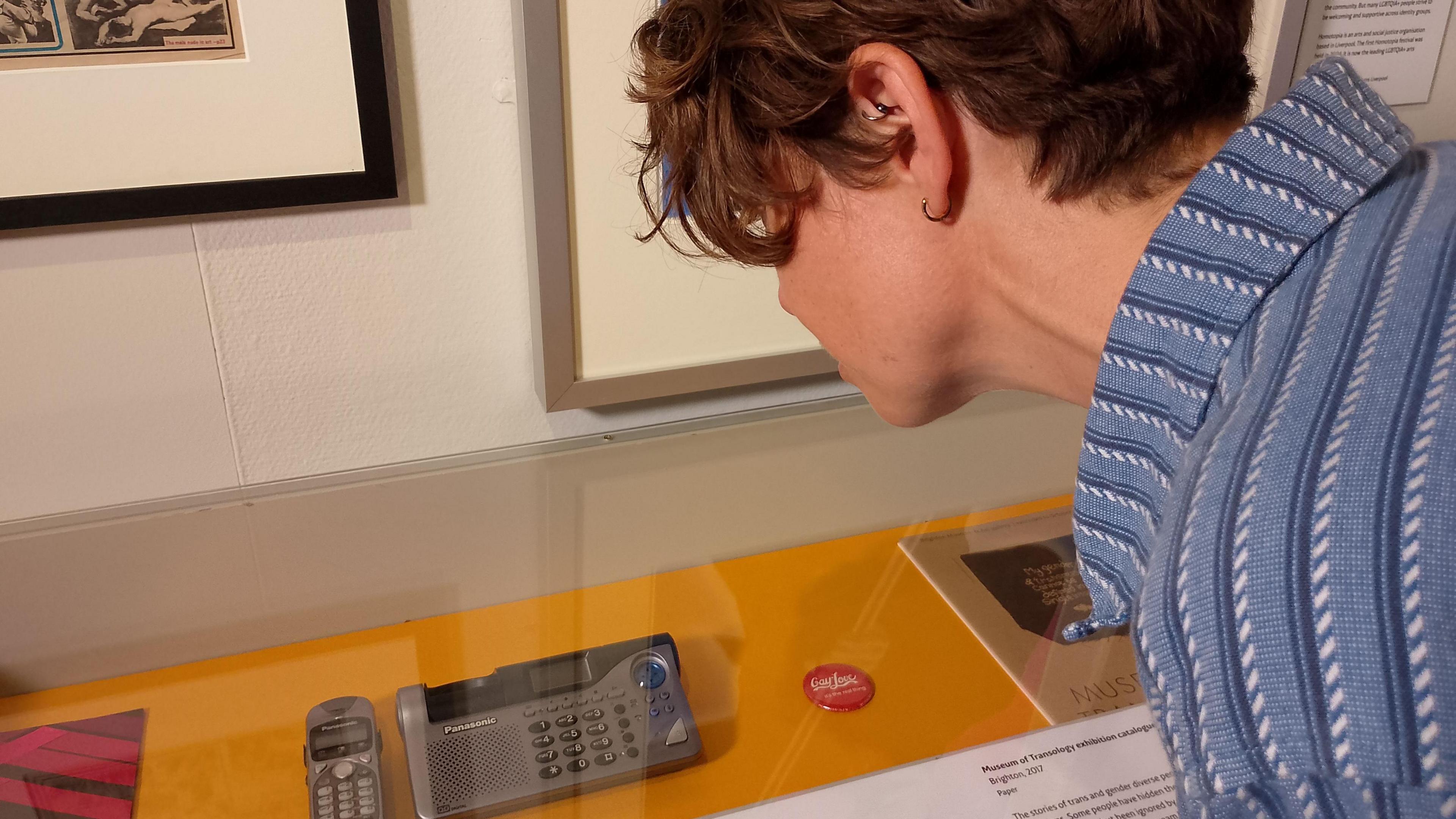 Tash Walker looking at the telephone she used, which is on display behind glass in Bristol Museum and Art Gallery. 