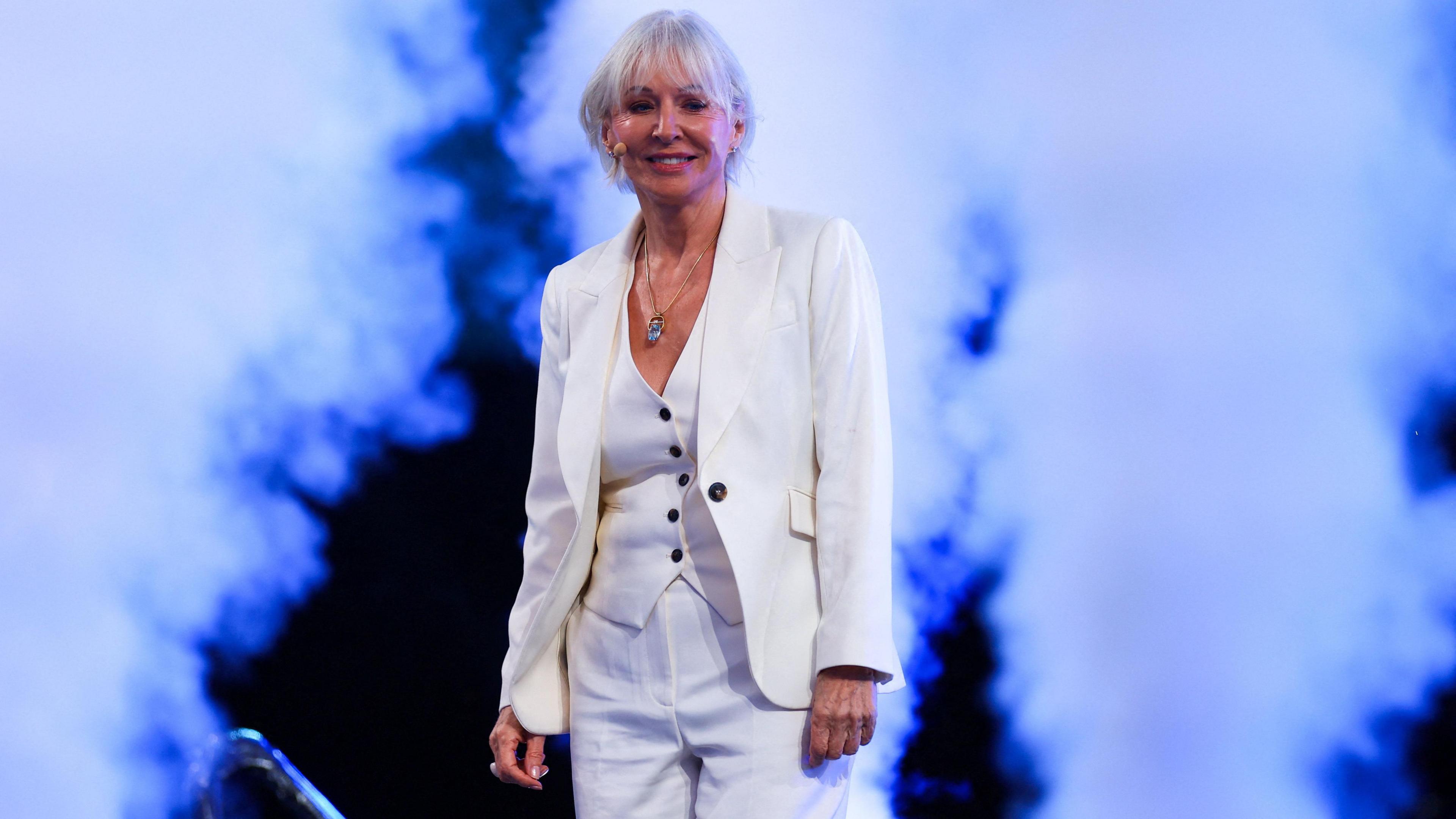 Nadine Dorries in a white suit, walks on to stage at the Reform UK conference with dry ice cannons firing either side of her.