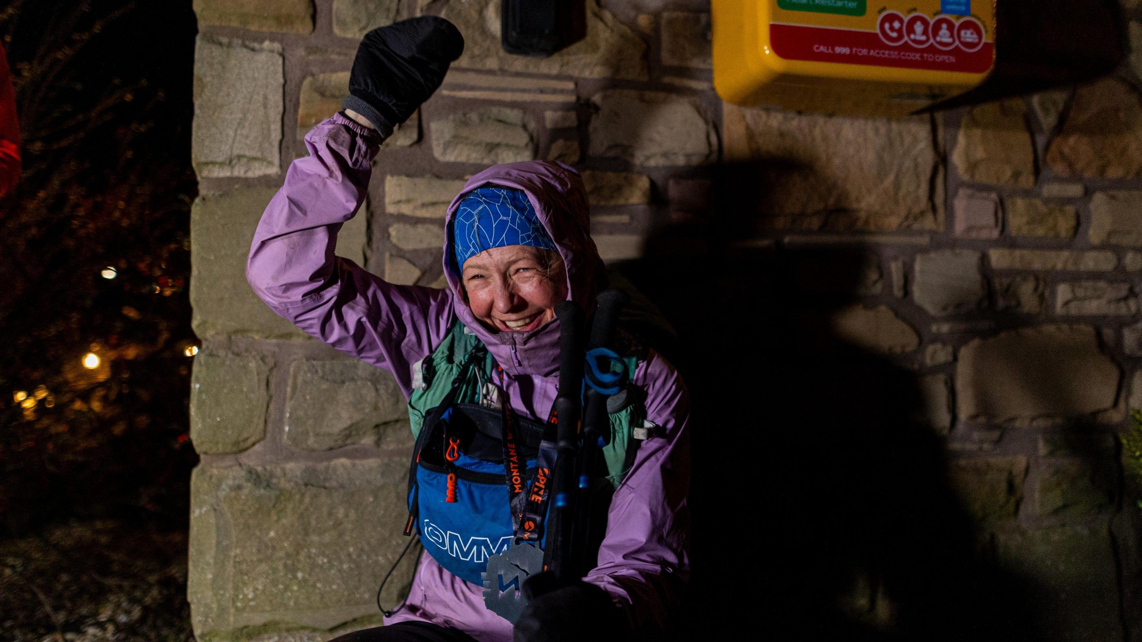 Gossage celebrates at the finishing line after winning the women's version of the huge race. She wears a purple jacket, has a beaming smile and is punching the air