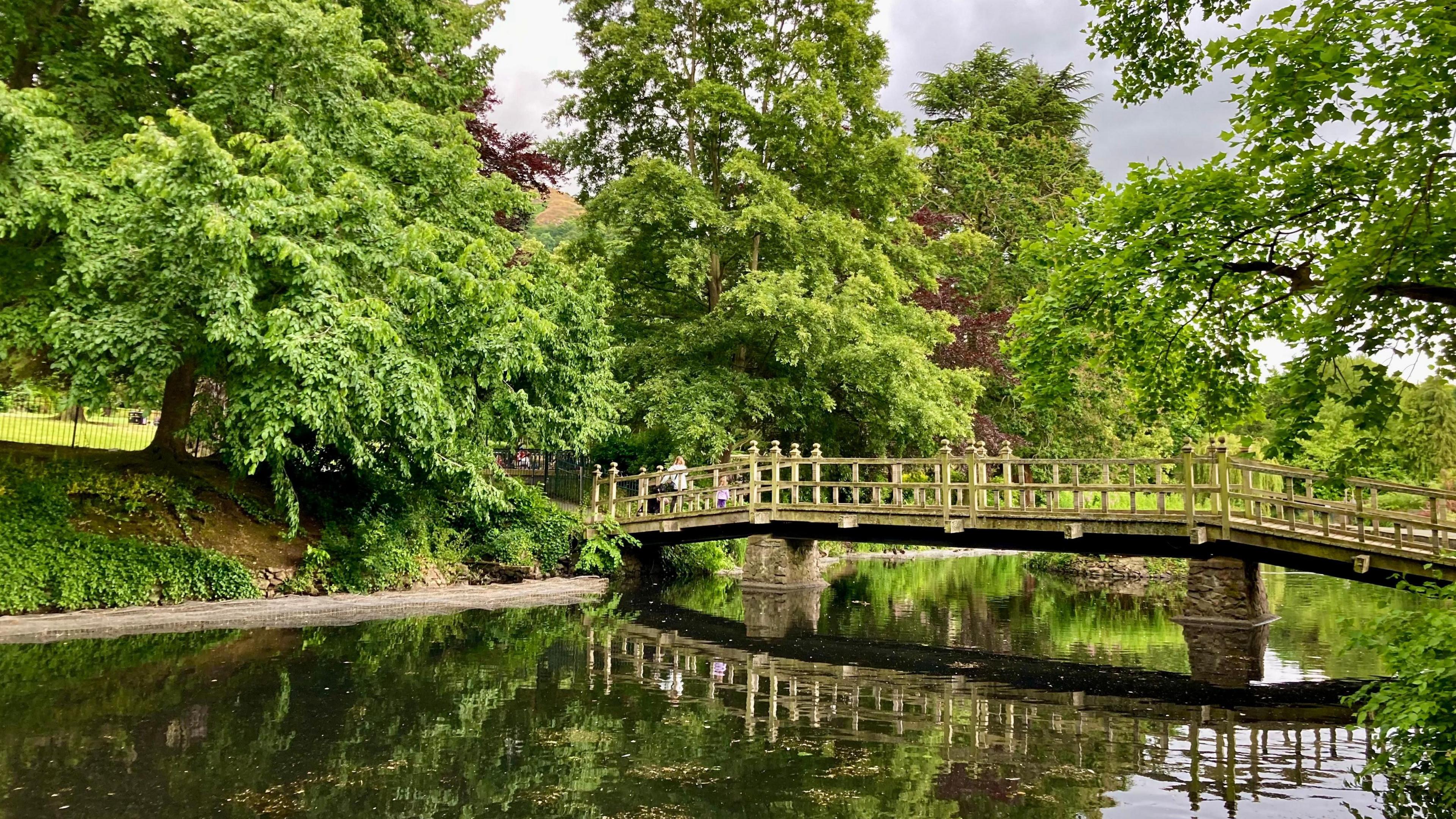 People make their way across a narrow wooden bridge in Malvern, as it stretches across a calm piece of water