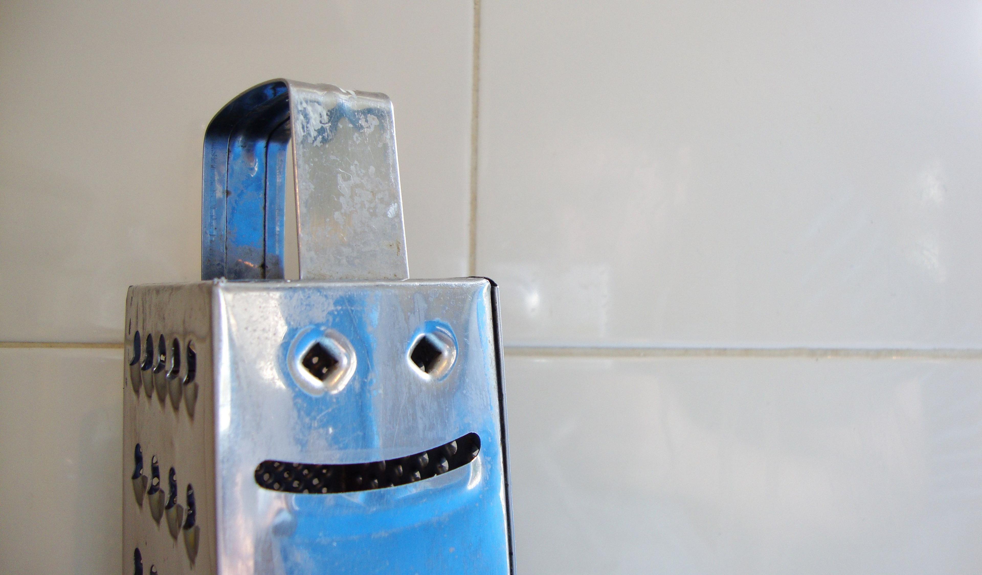 A cheese grater with indentations that looks like a smiley face. 