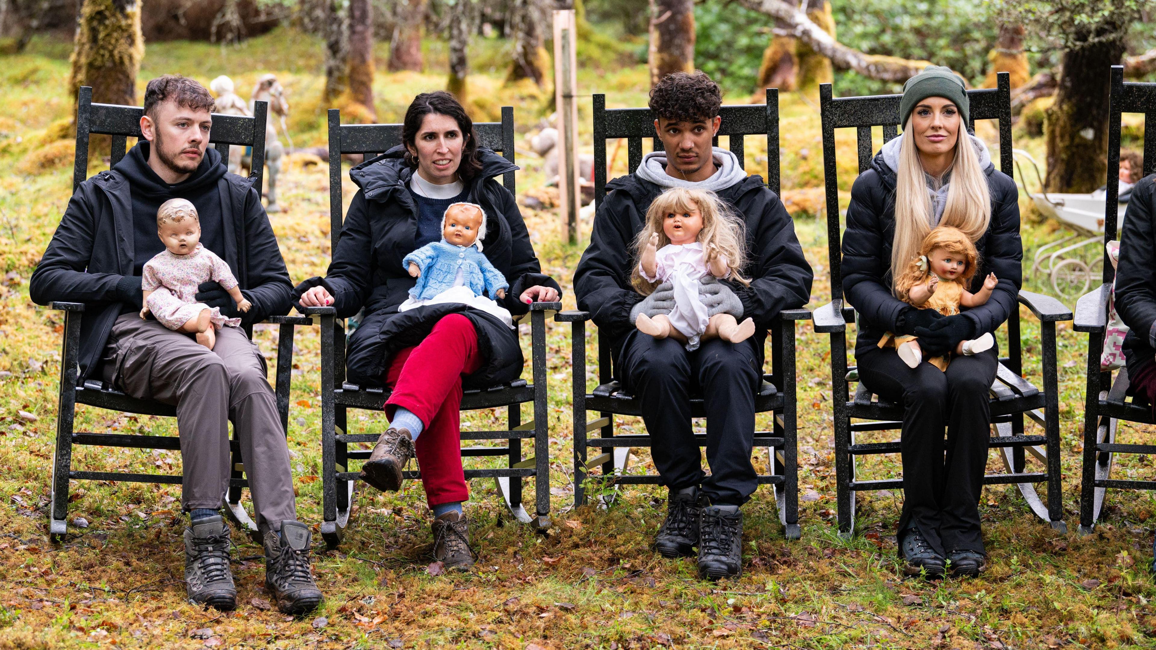 Traitors contestants Jake, Charlotte, Freddie and Leanne sit outside in wooden chairs with dolls on their laps 