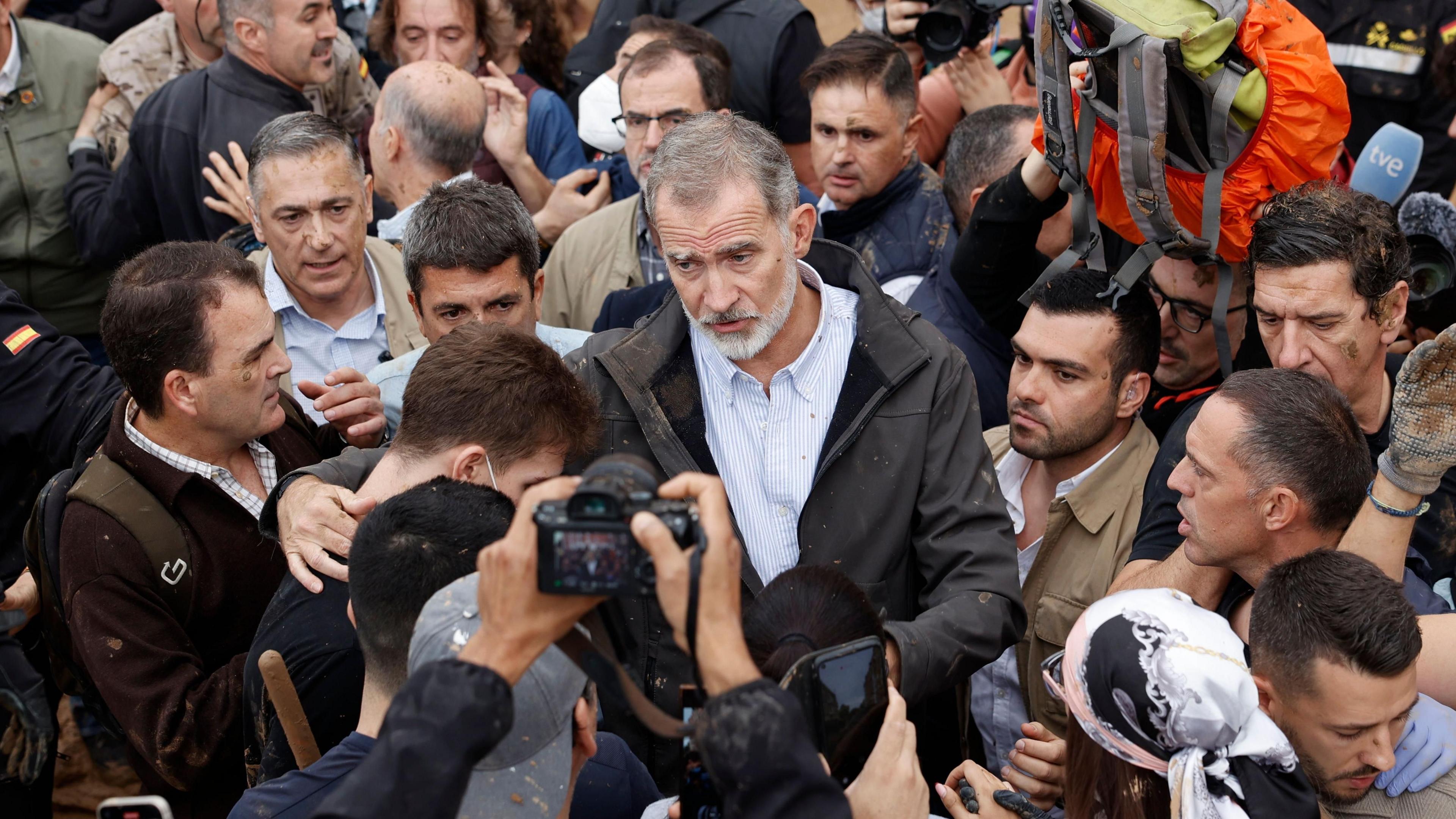 King Felipe of Spain in a large group of people, he has his arm around one man.