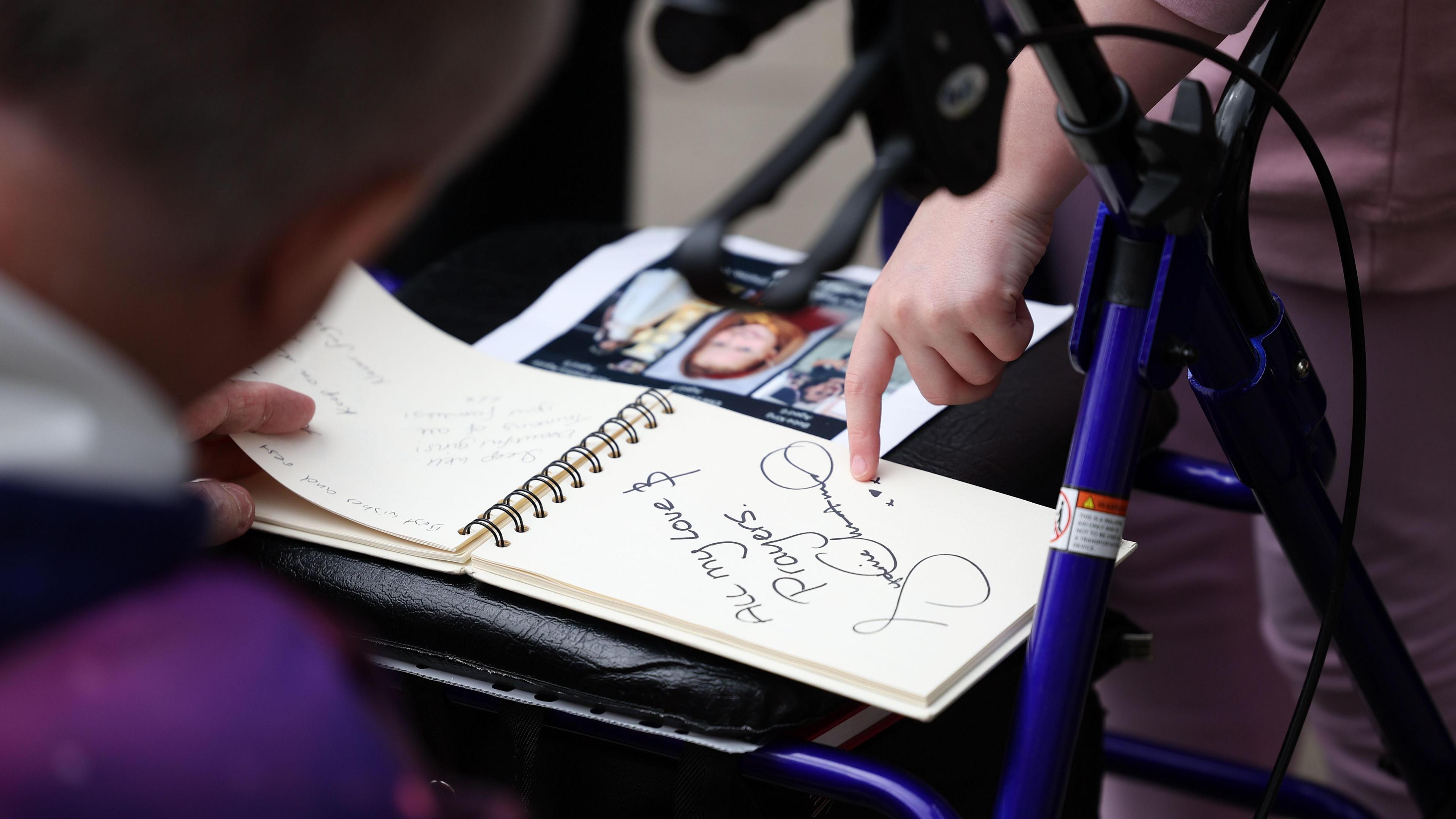 People view last year's book of condolence which is placed on a mobility aid.