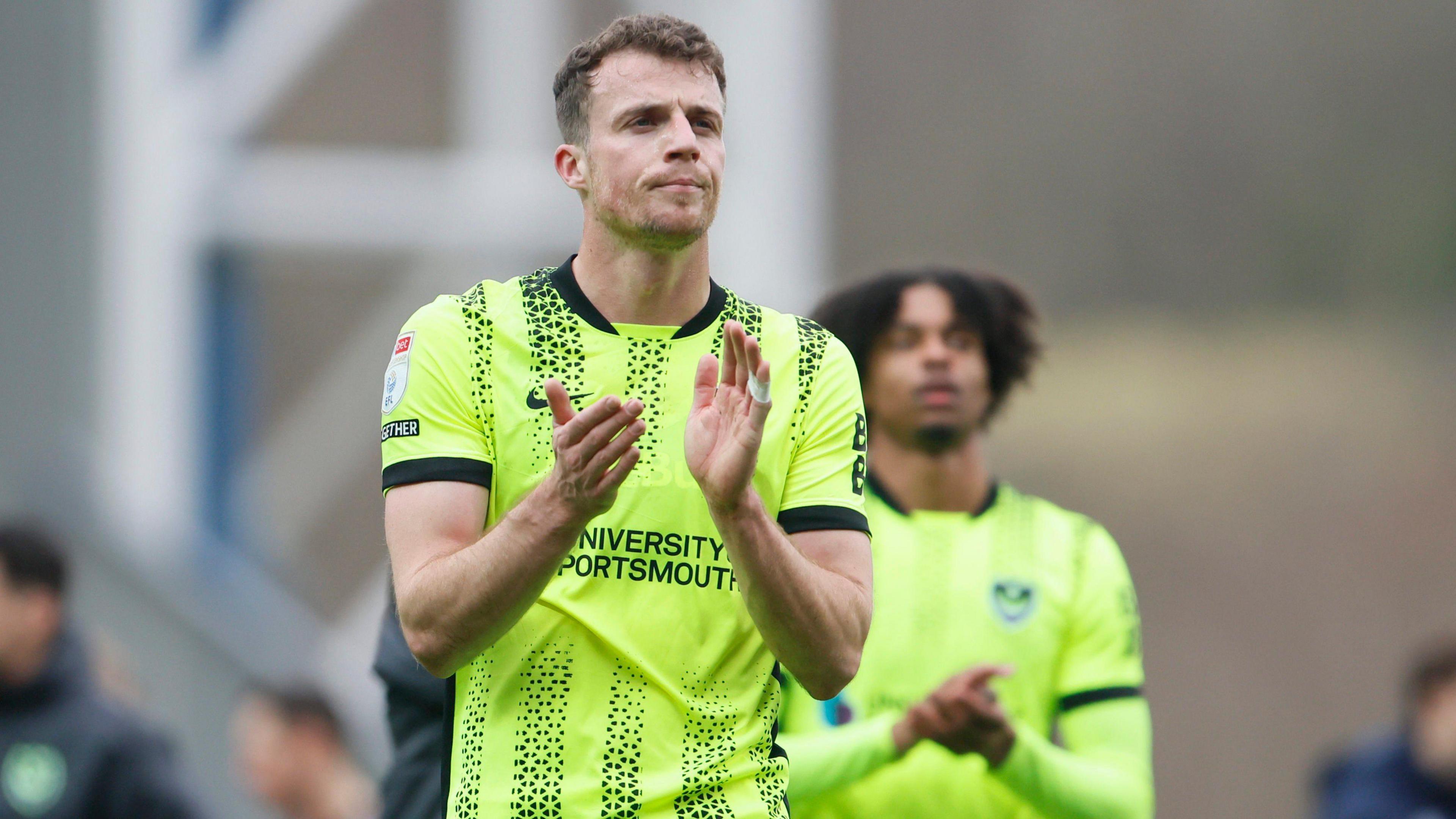 Disappointed Portsmouth's Conor Shaughnessy wearing a lime green shirt and shorts applauds the fans at full time during the Championship match between Blackburn Rovers and Portsmouth 