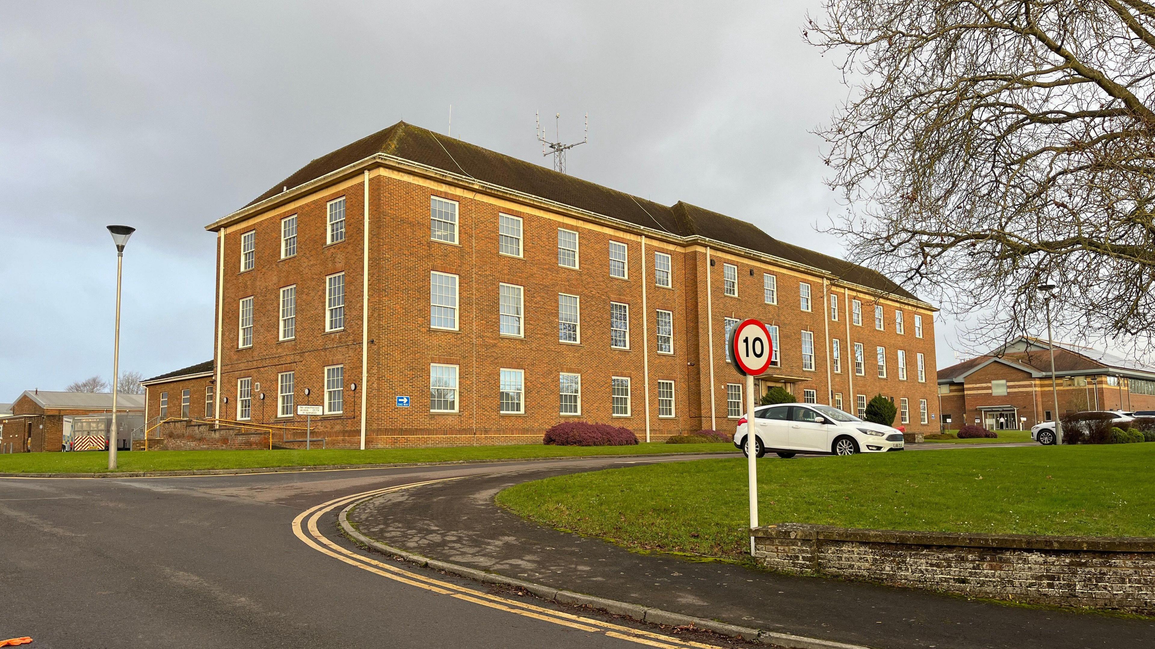 Wiltshire Police HQ in Devizes. The building is red brick and has lots of windows. 