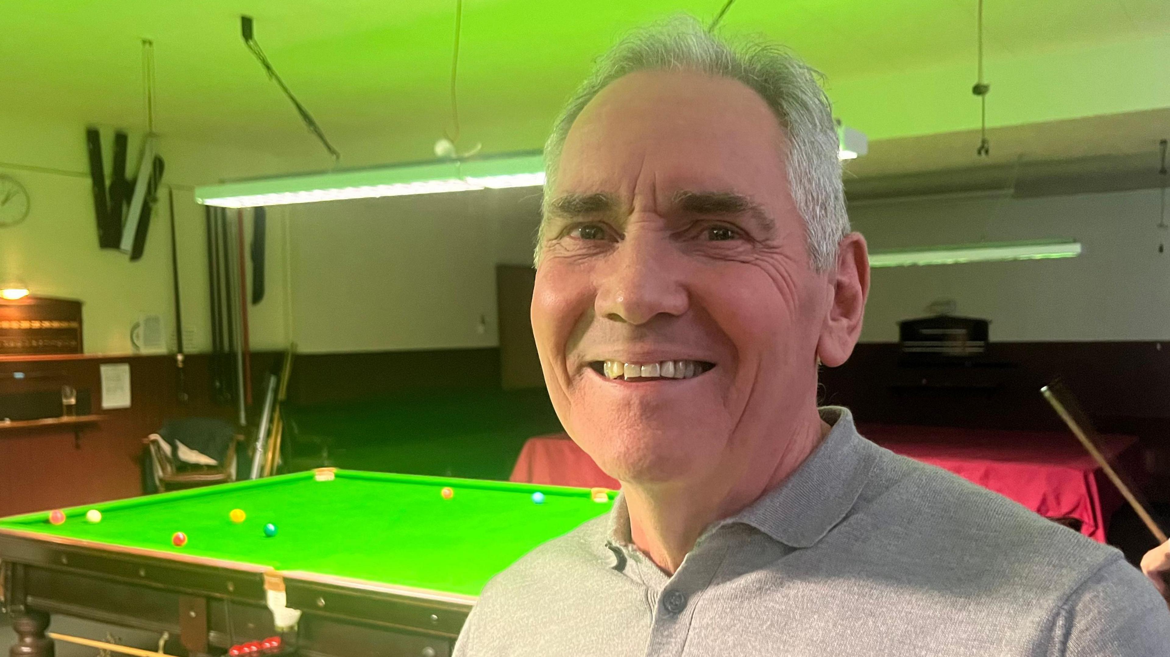 Russell Leggett, wearing a grey top. Behind him is a snooker table.