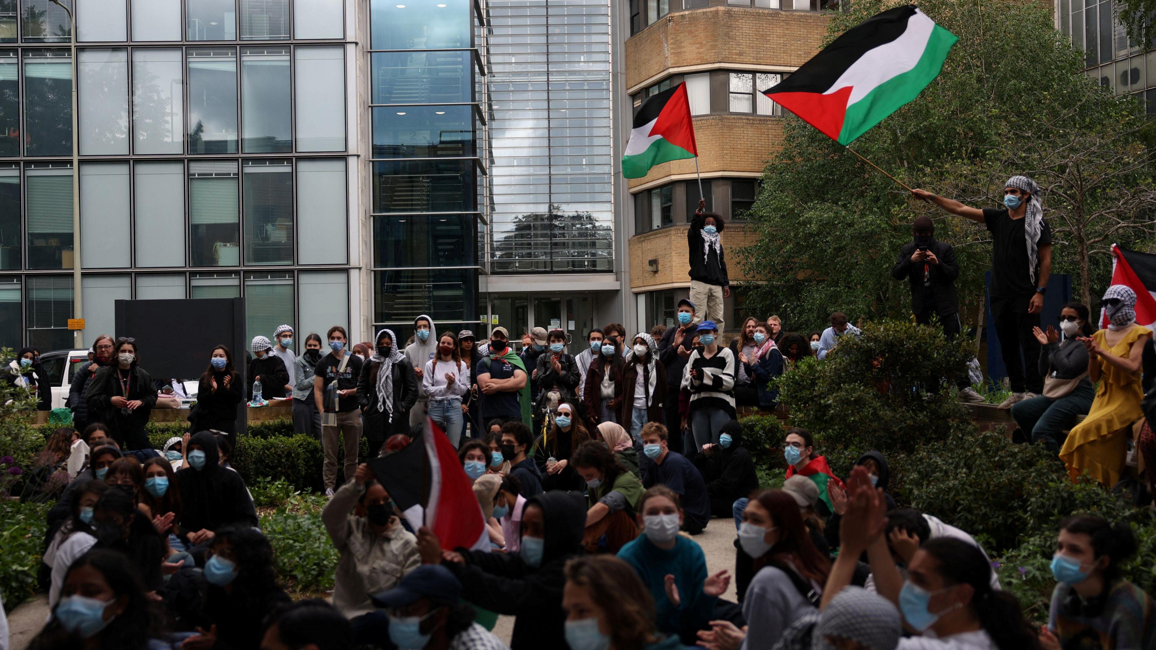 Protesters stand in front of a university building during a demonstration in support of Palestinians, at Oxford University, amidst the ongoing conflict.