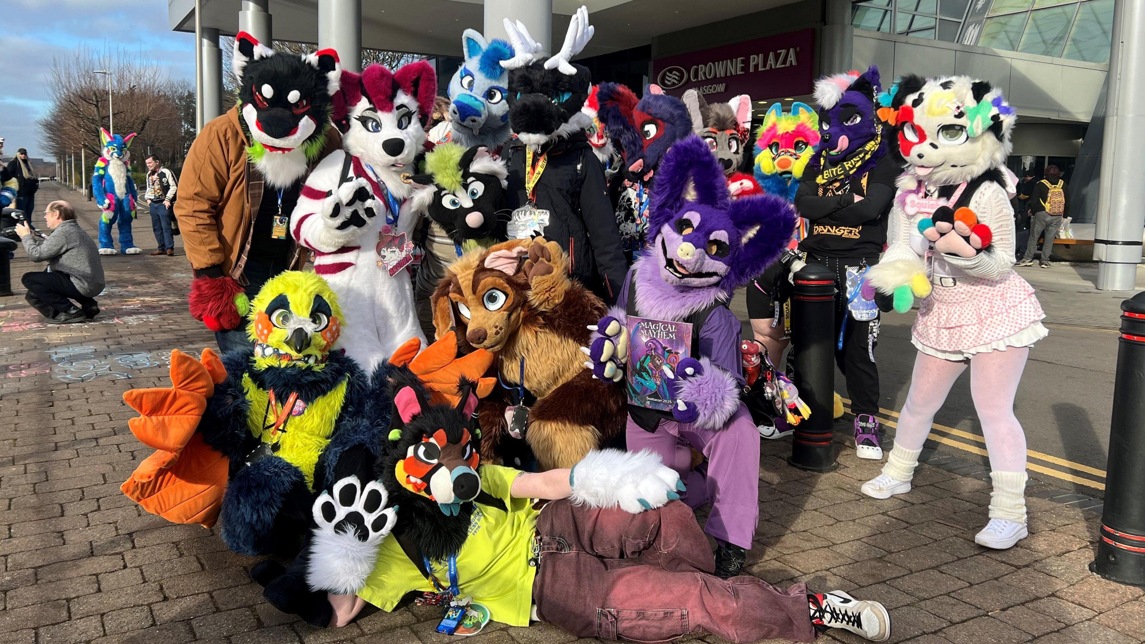 A group of people dressed as furries. The group includes someone dressed as a yellow canary, a purple fox and a black reindeer. 