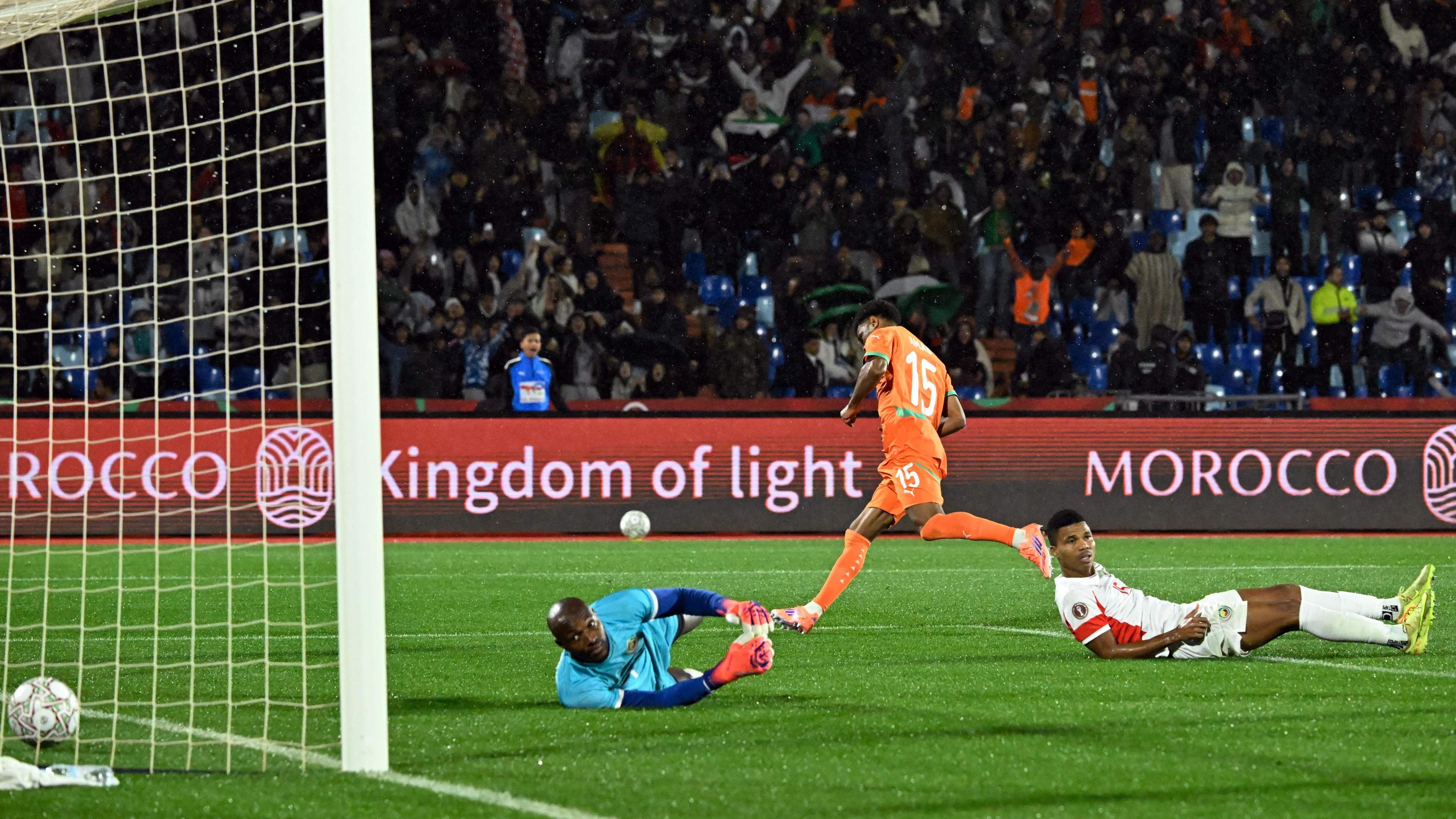 Ivory Coast forward Amad Diallo, wearing an all-orange strip, streaks away in celebration as Mozambique goalkeeper Ernan and Reinildo lie prostrate on the floor