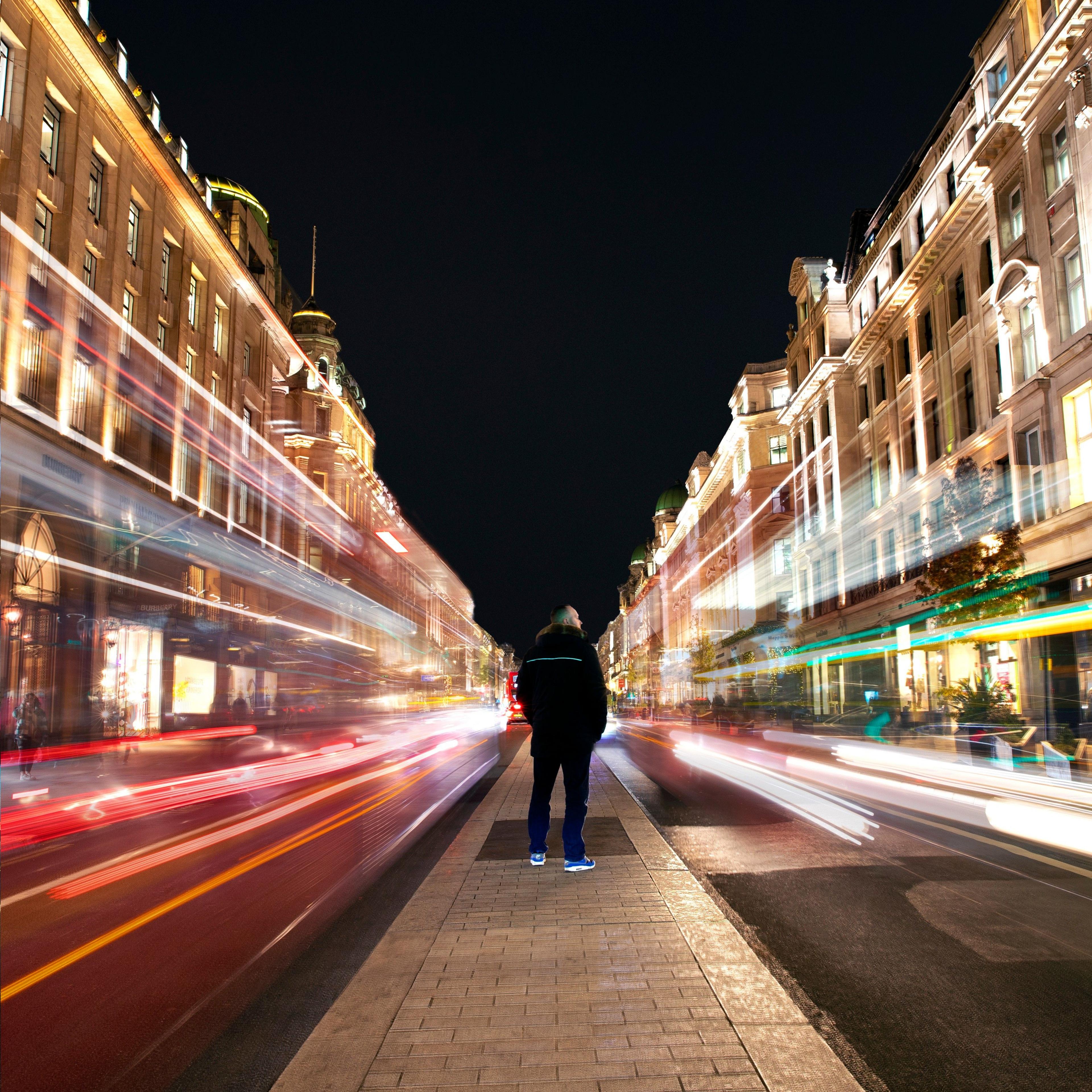 A man stands on the central section of Regent Street in London as cars pass on either side