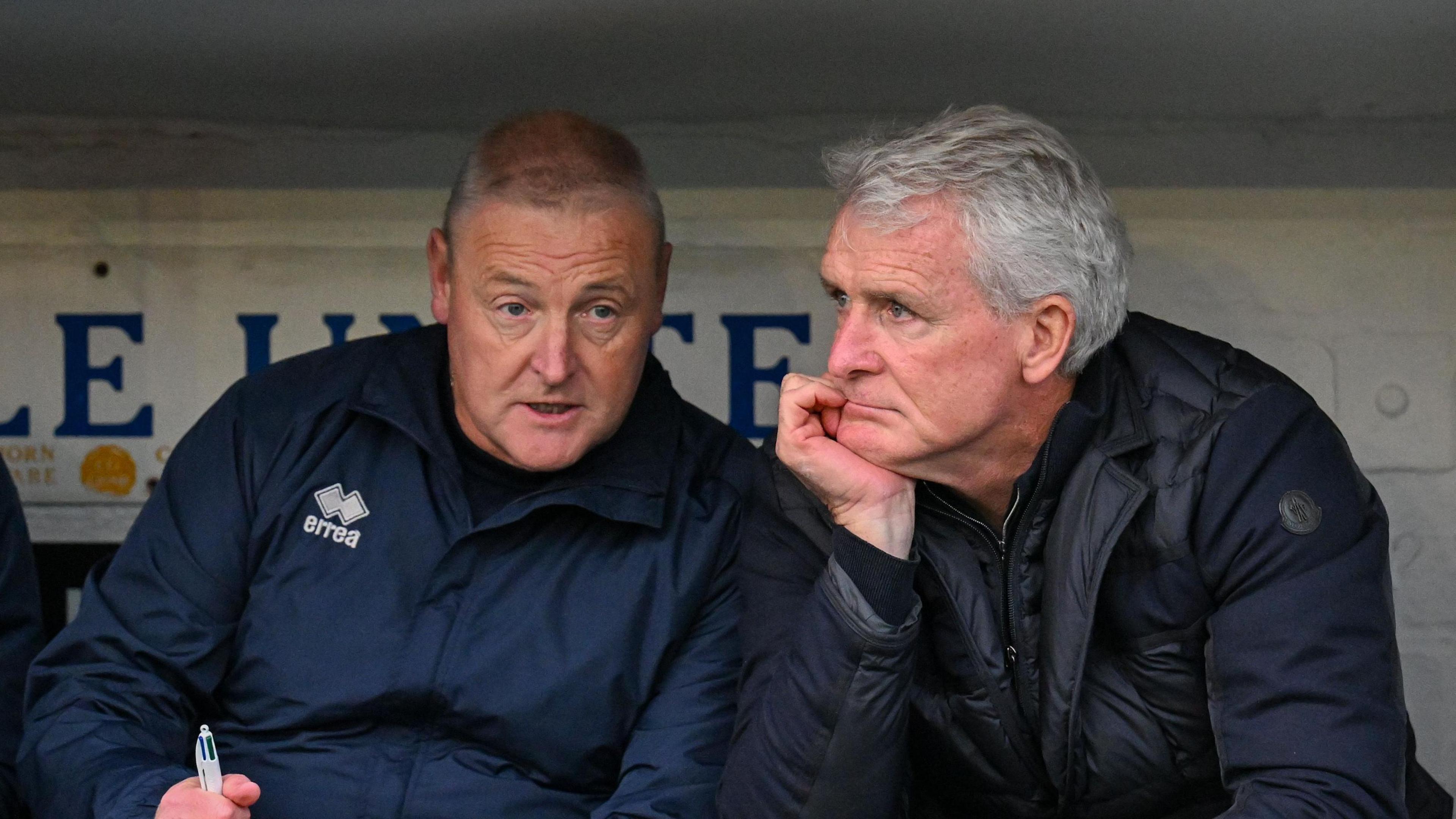 Mark Hughes (right) listening to Carlisle assistant Frankie McAvoy in the dugout 