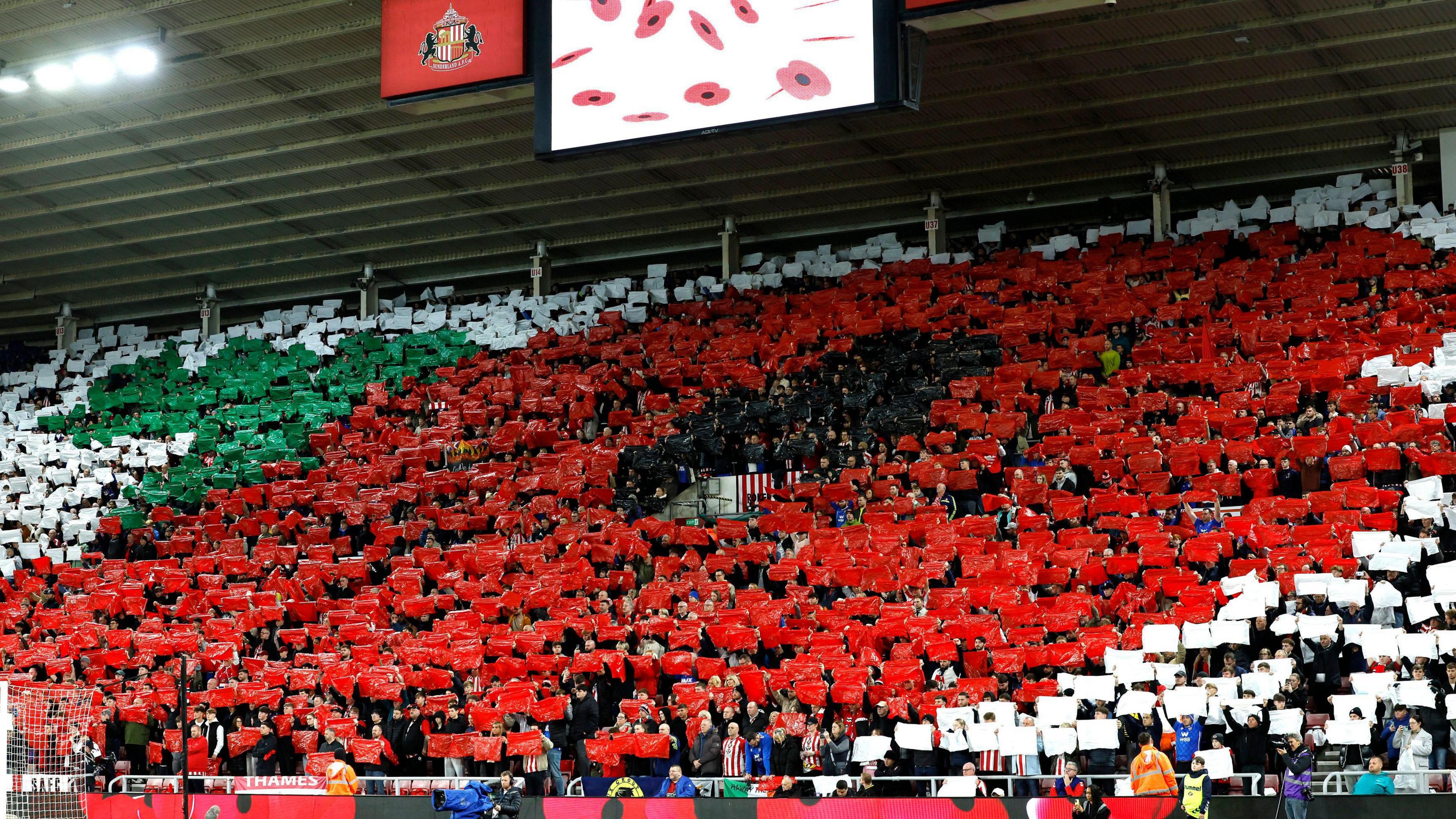 A general view of a poppy tifo display for Remembrance Sunday before the Premier League match at the Stadium of Light, Sunderland. Hundreds of people are holding up coloured sheets of plastic which depicts a giant red and black poppy.