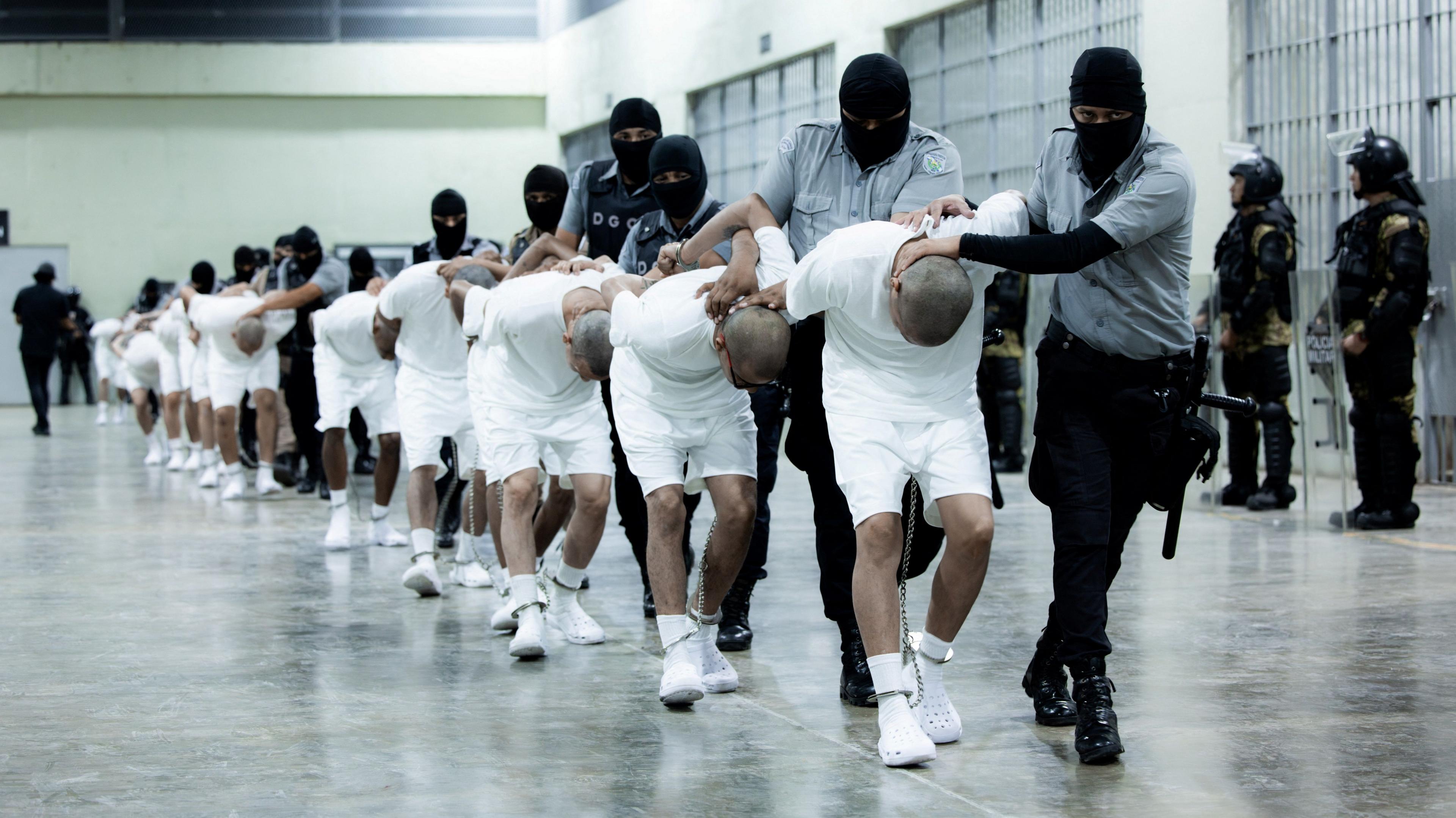 Salvadoran police officers escort alleged members of the Tren de Aragua to a detention centre.