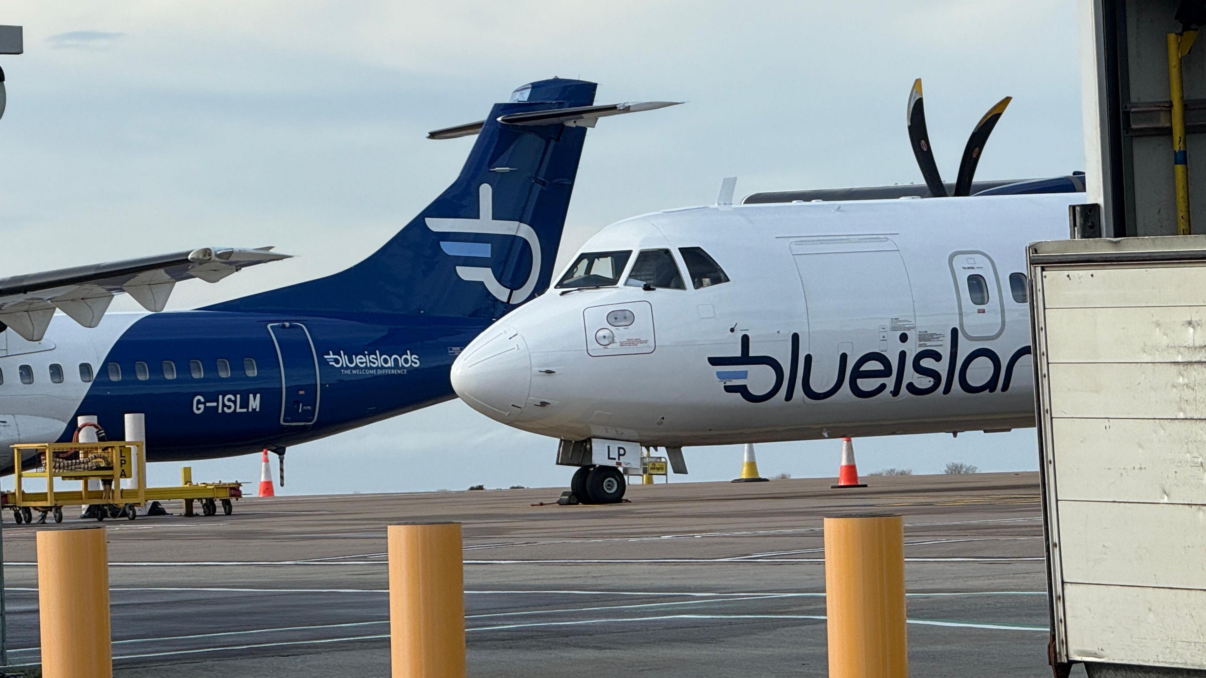 Two Blue Islands aircrafts on the tarmac at Guernsey Airport. Clouded blue skies can be seen behind.