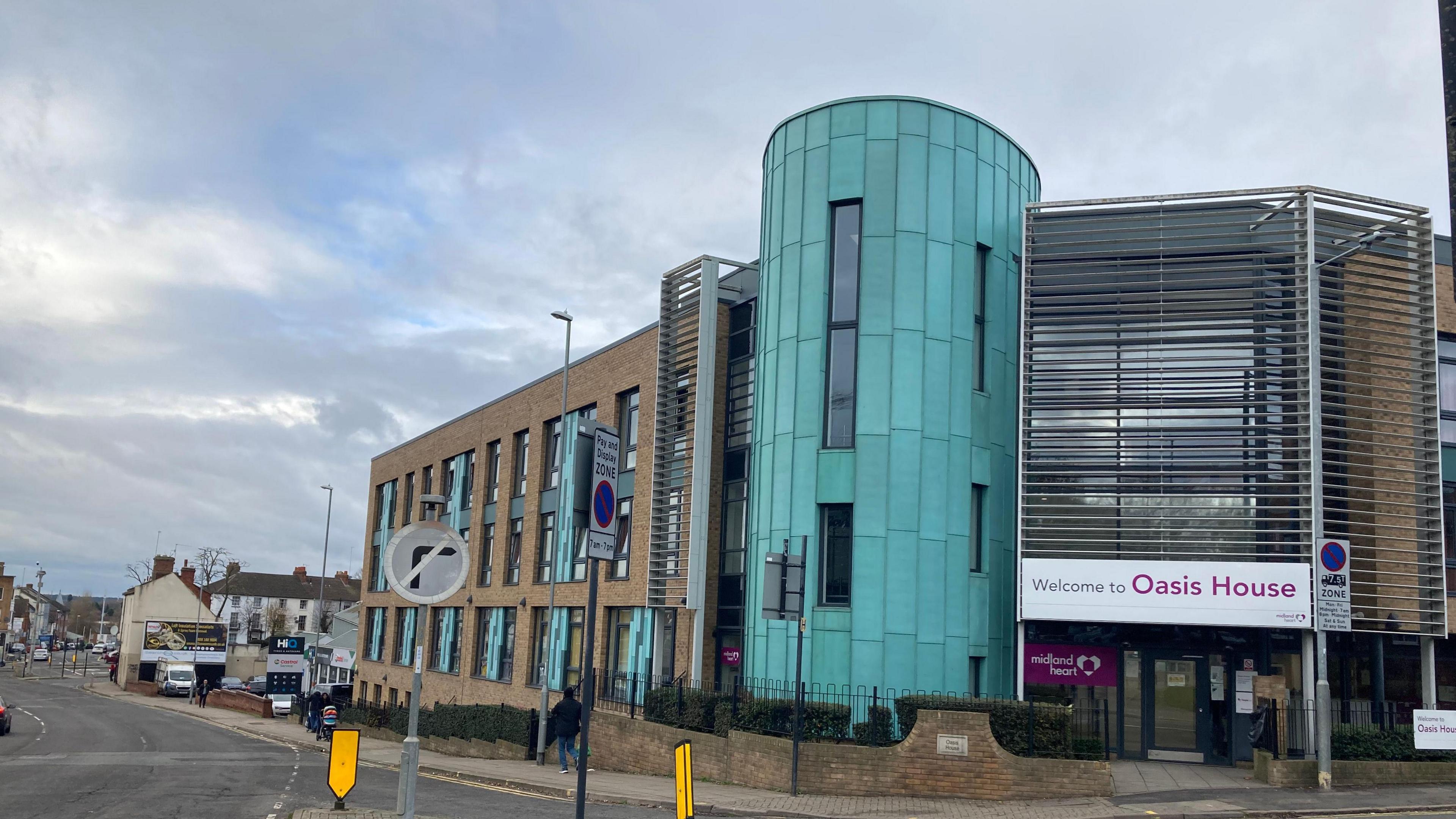 A street view of the entrance to the Hope Centre - a brick building that has a turquoise tower on the front. 