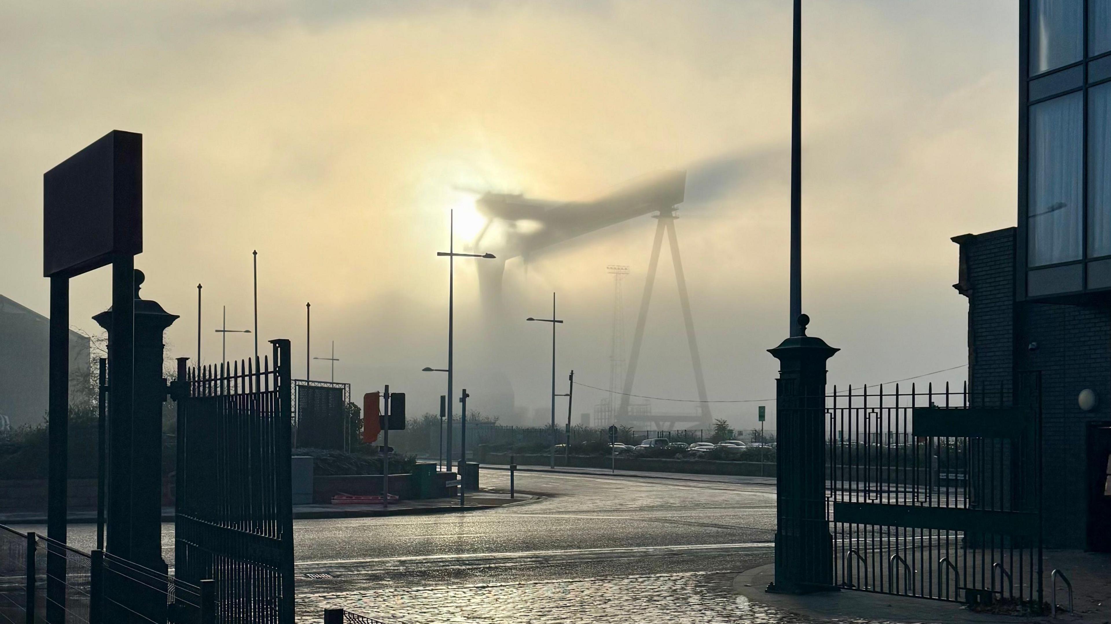 One of the two Harland and Wolff cranes which dominate the Belfast skyline is obscured by fog on Thursday.   Only a dark outline of the crane is visible because of the thick blanket of fog across the docks area of the city.  The sun is in the background illuminating the crane.