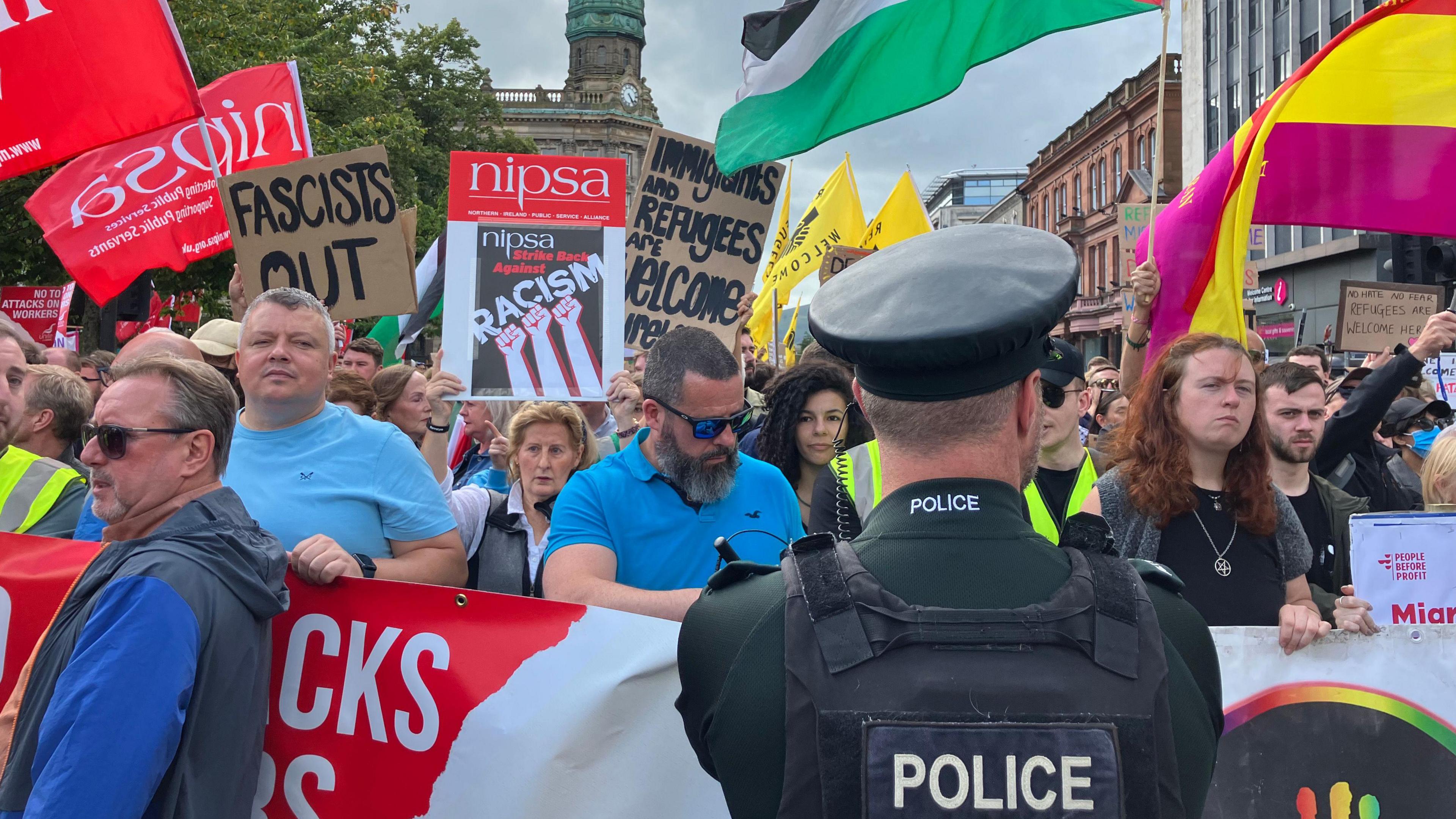 Colourful flags, banners and placards saying 'fascists out' and 'immigrants and refugees are welcome' 