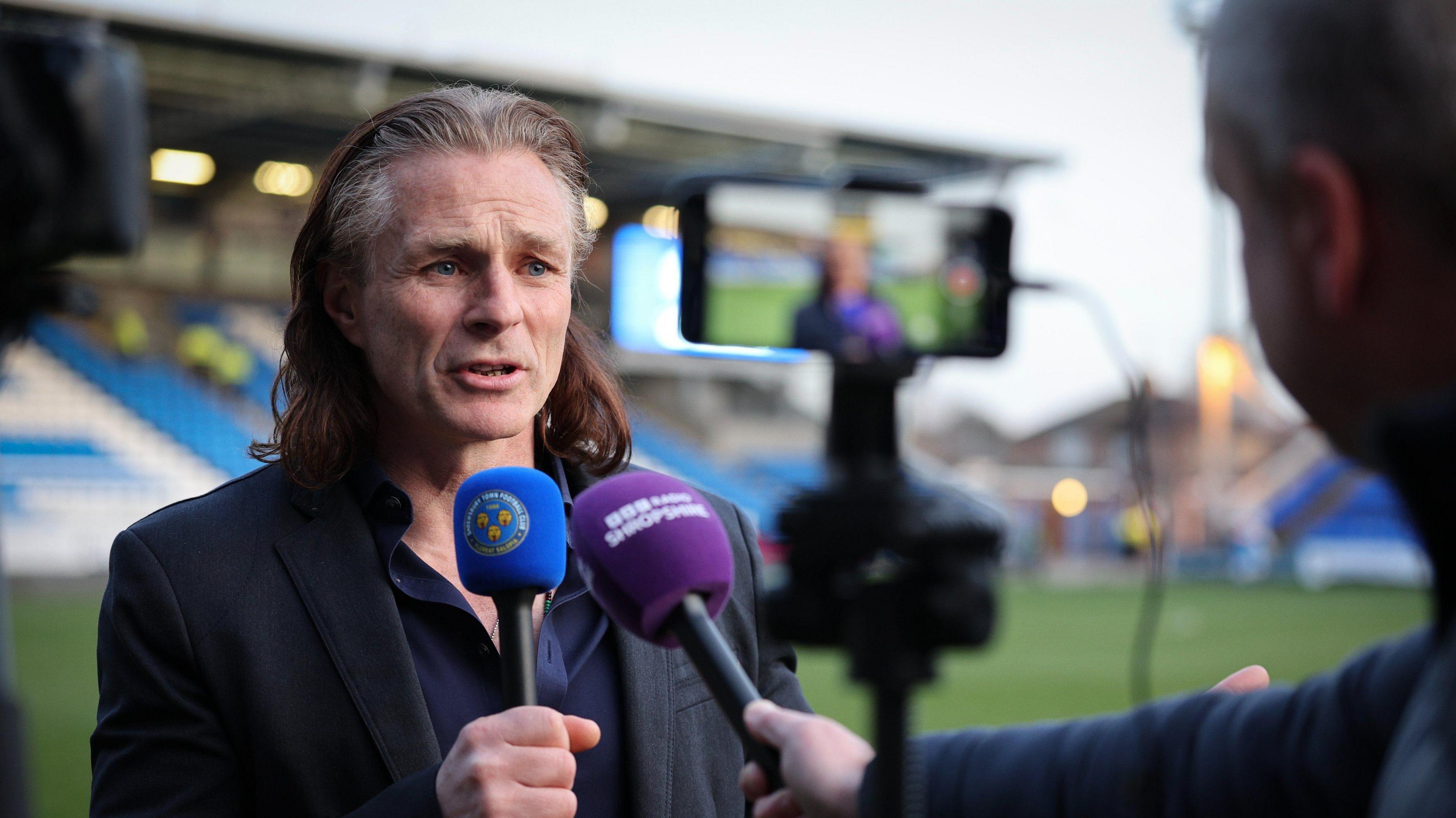 Gareth Ainsworth being interviewd by BBC on the side of the pitch
