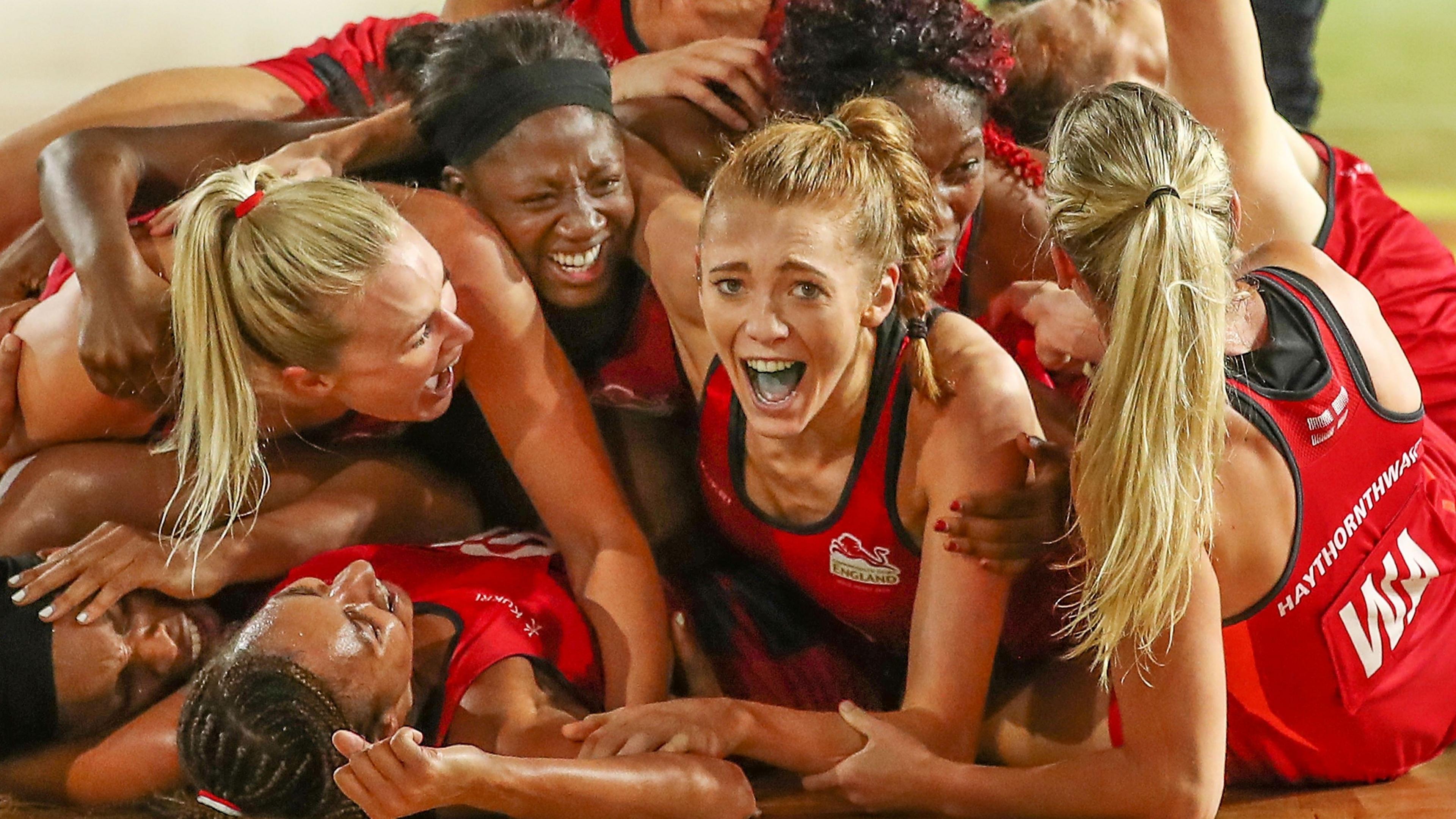 Helen Housby lies forward on the ground, celebrating with her England team-mates, her tongue blue