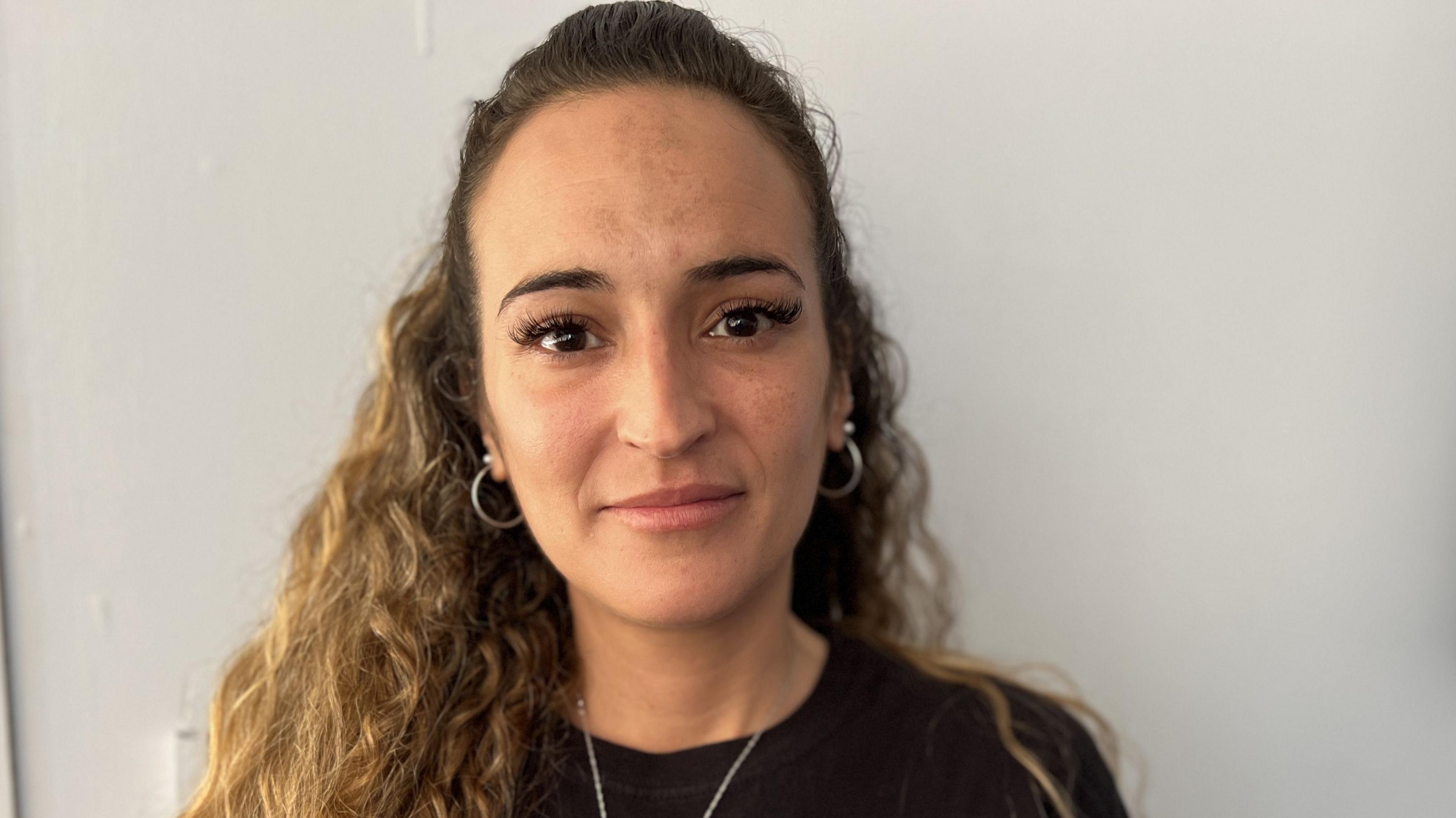 Gemma Page with long curly hair tied back wearing a black Owen's World t-shirt