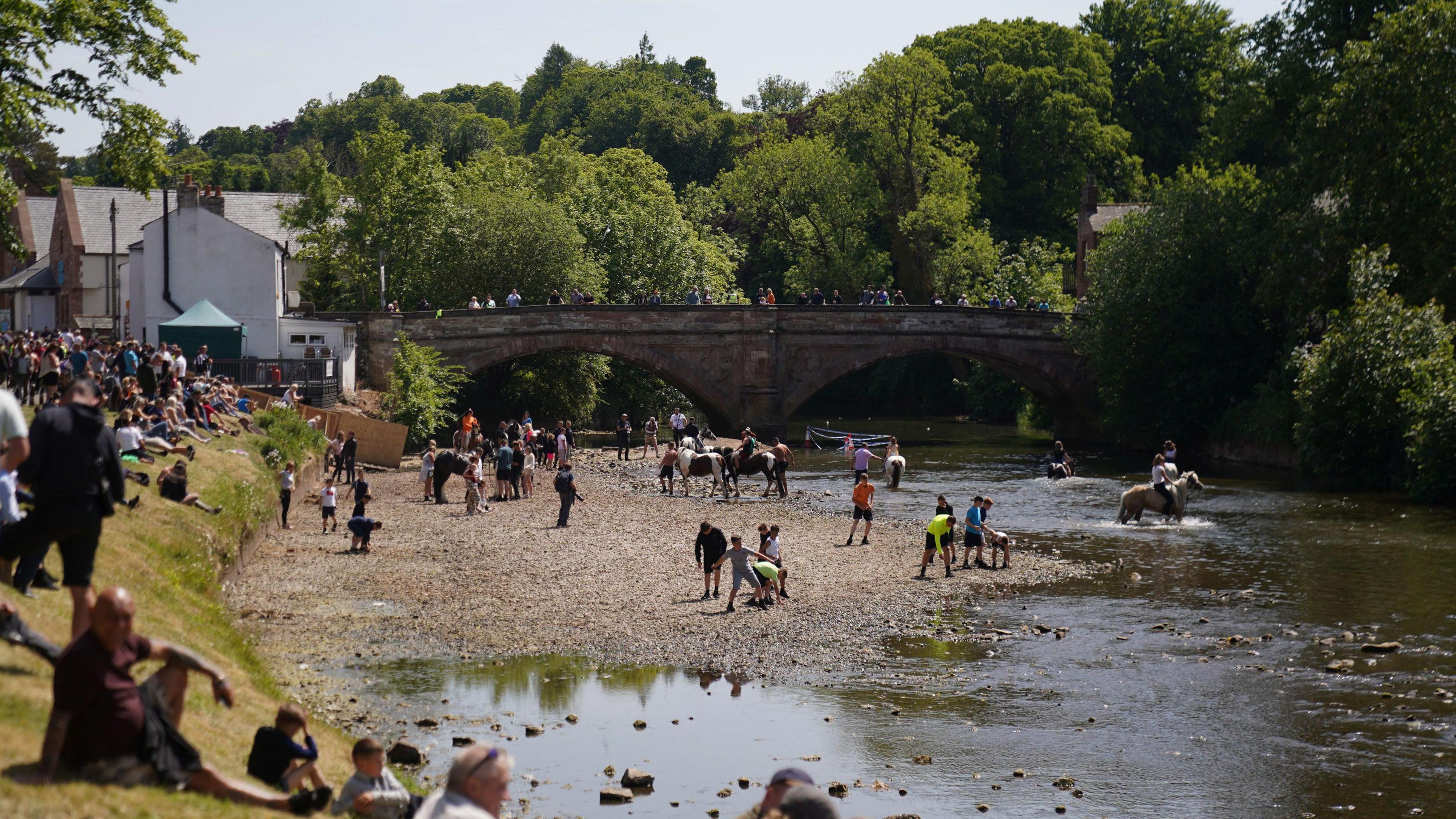 People ride their horses through the river during the Appleby Horse Fair