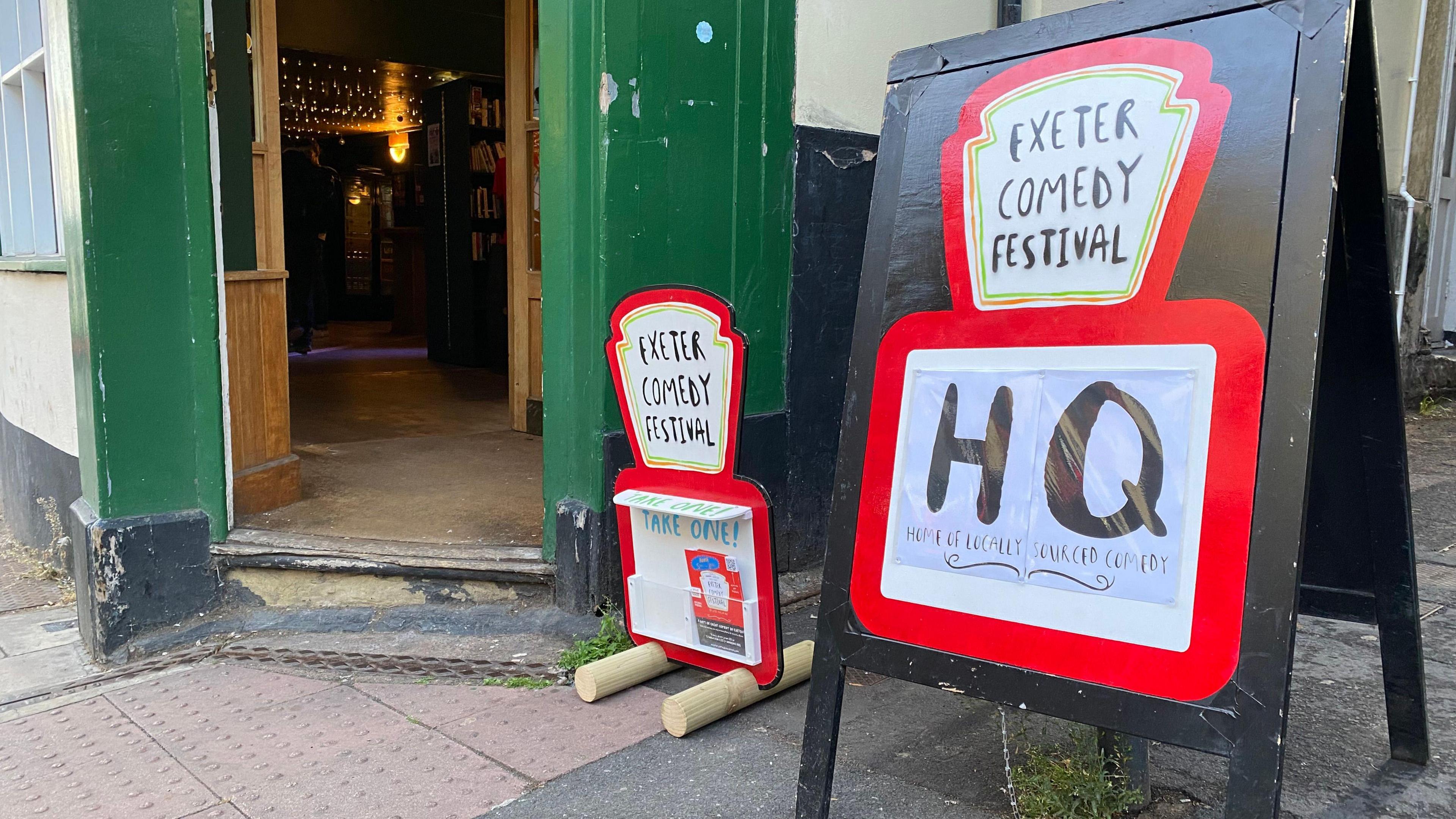 A sign with the words 'Exeter Comedy Festival HQ' written on it outside a pub