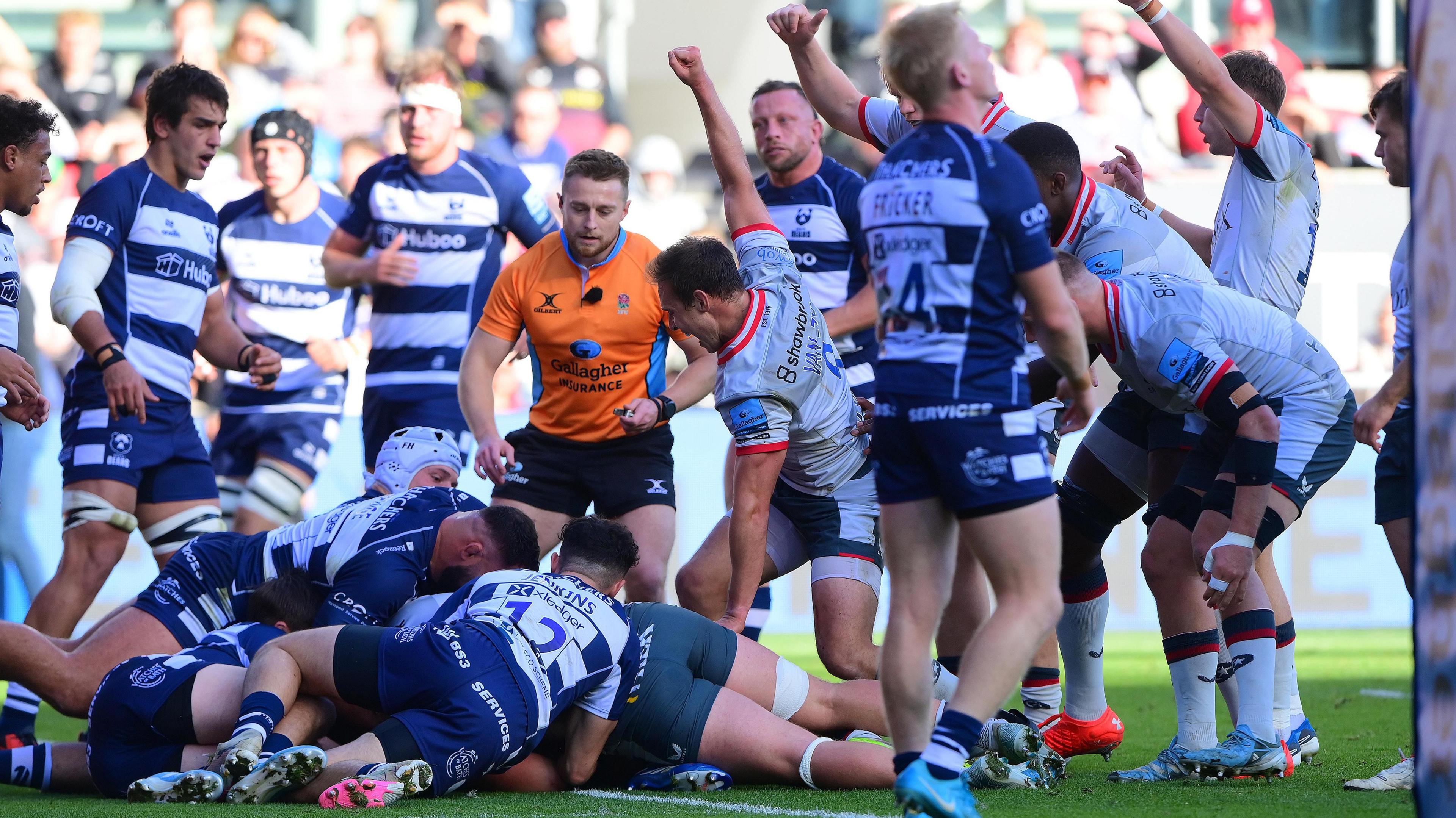 Saracens players celebrate a try while Bristol players look dejected 