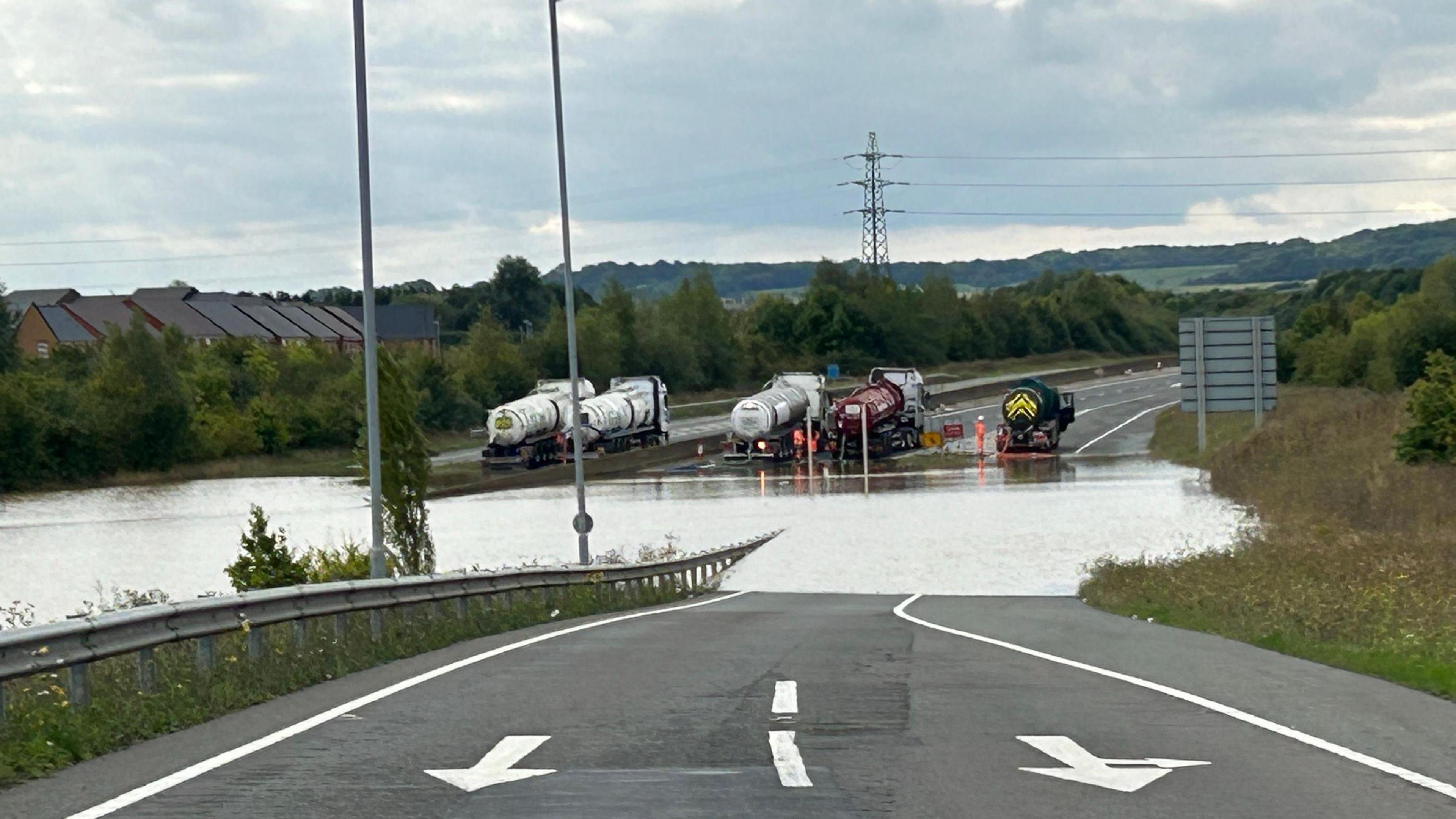 Five tankers are lined up across the A421 near Bedford and are pumping water from the carriageway