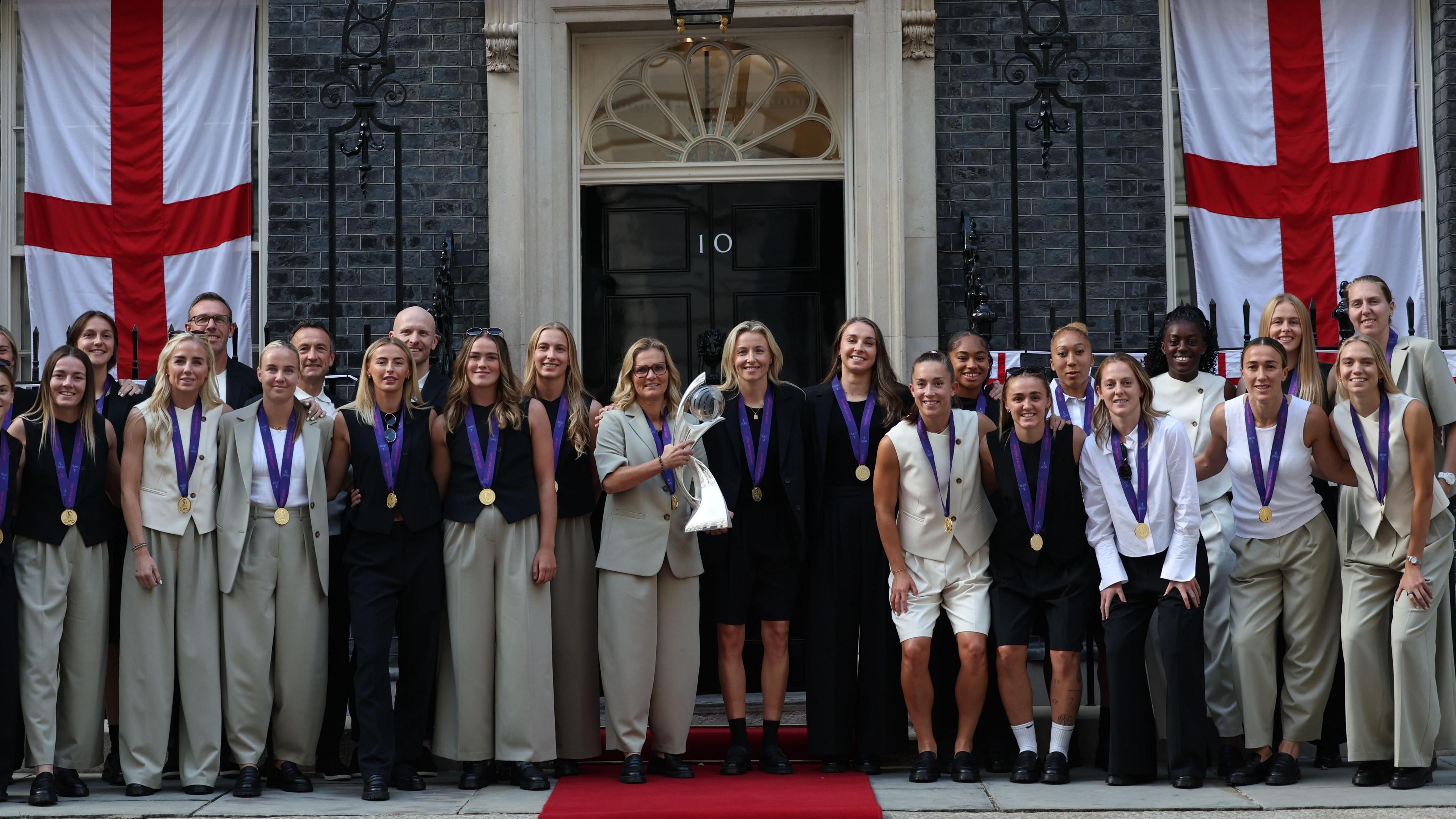 The England squad standing outside number 10 downing street while holding the euro 2025 trophy