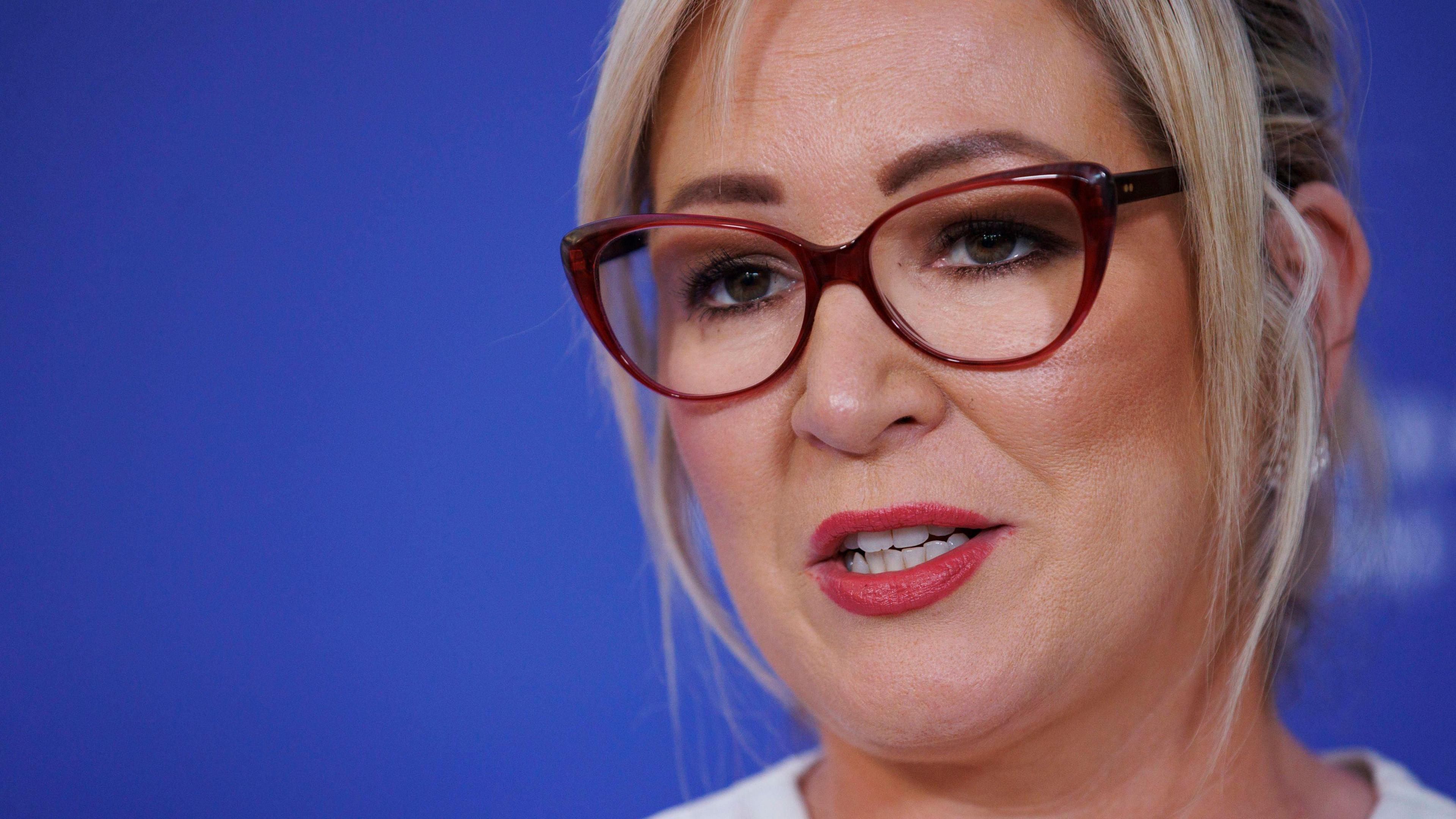 Michelle O'Neill. She has blonde hair tied back and brown eyes wearing tortoise shell glasses and white top.