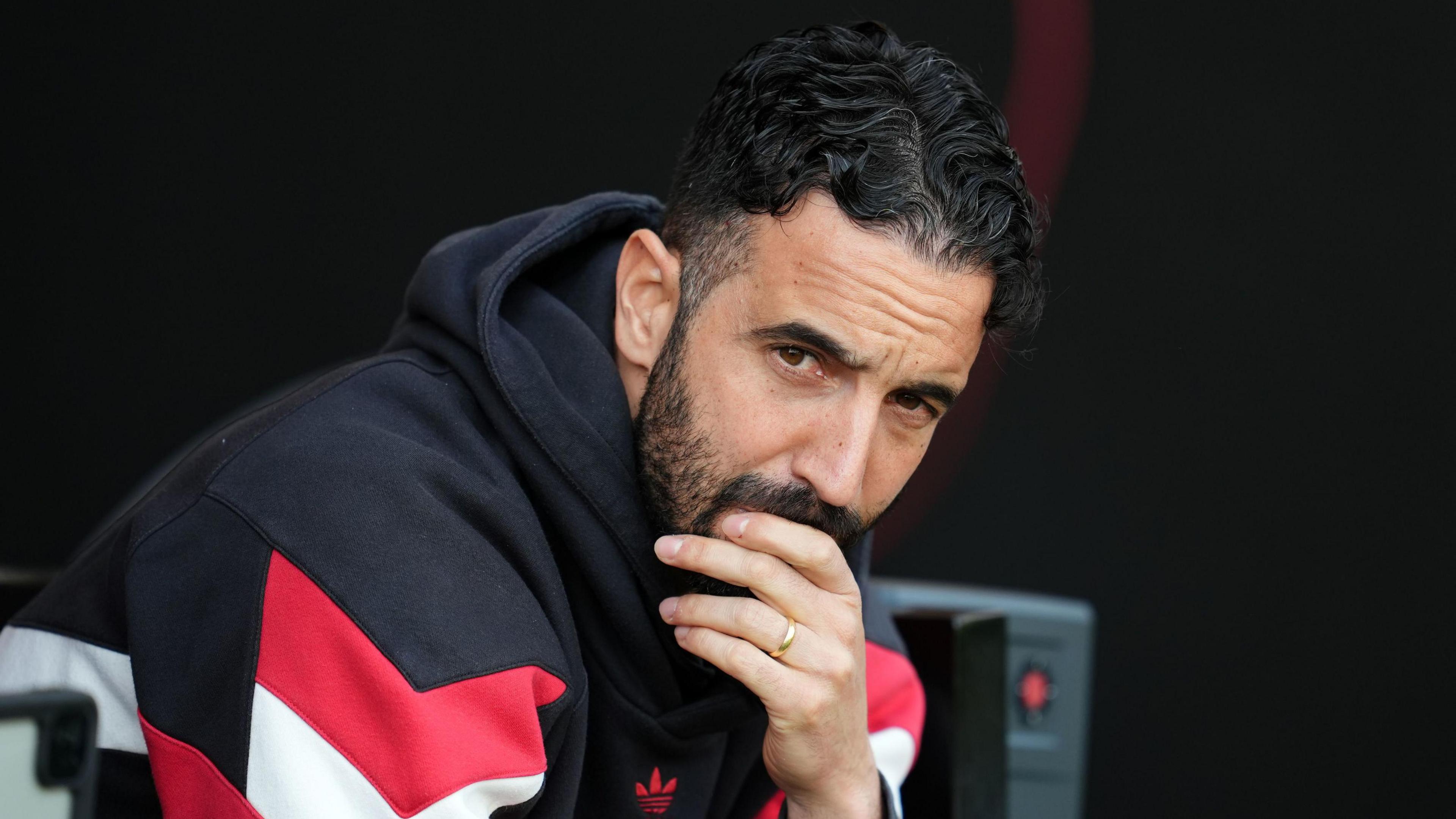 Ruben Amorim wearing a black, white and red hoodie holding his hand to his mouth.