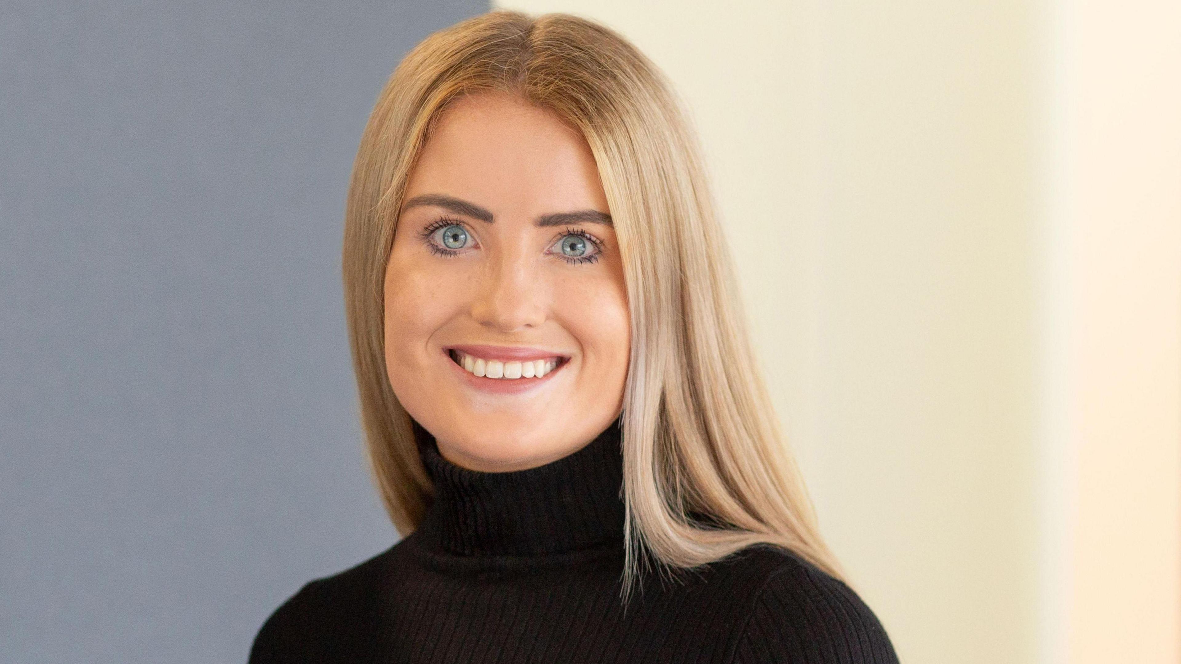 Headshot of Simone White smiling and looking at the camera in a black turtleneck