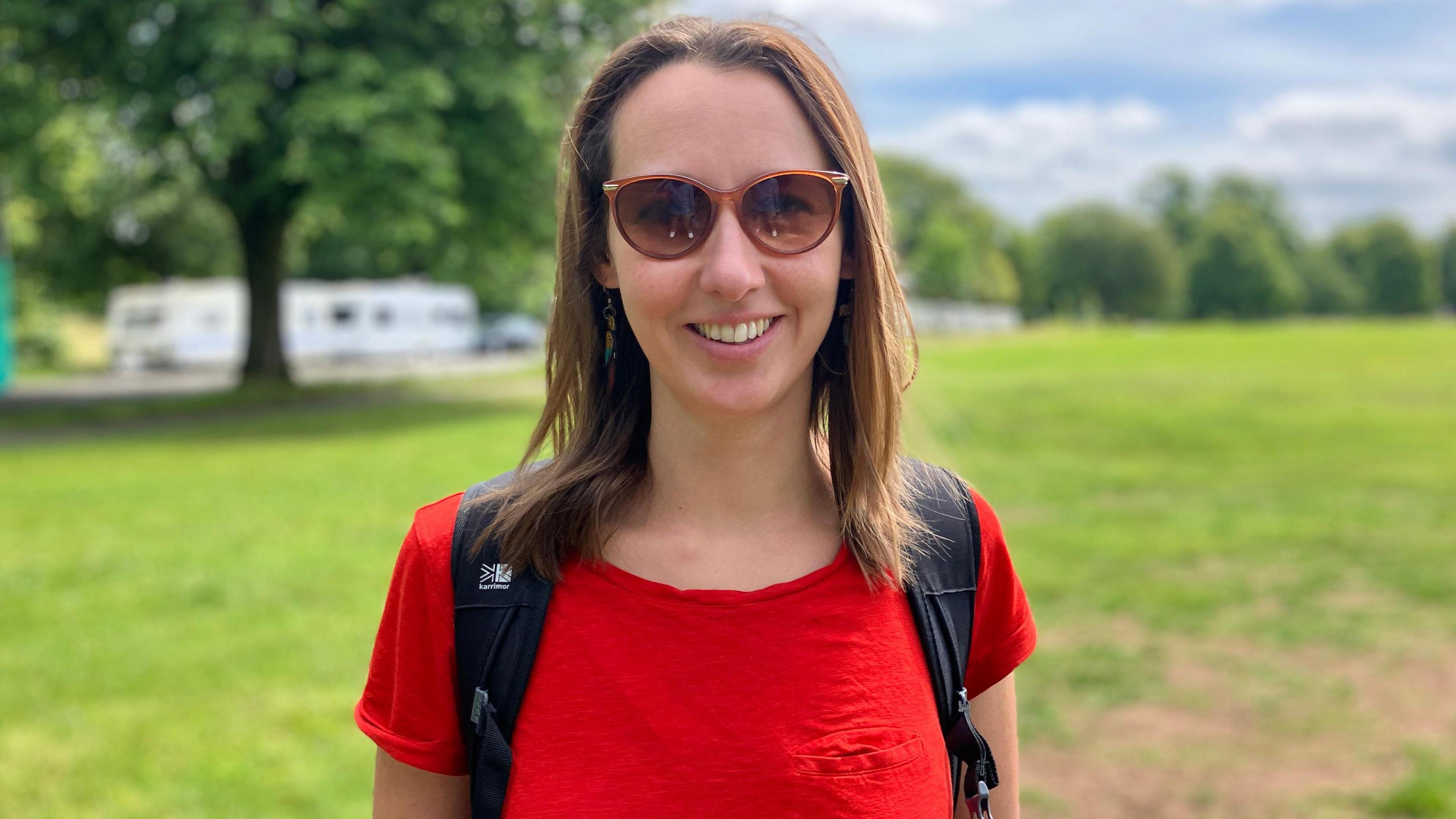 Nicola West. She is pictured outside, wearing sunglasses and a red t-shirt. 