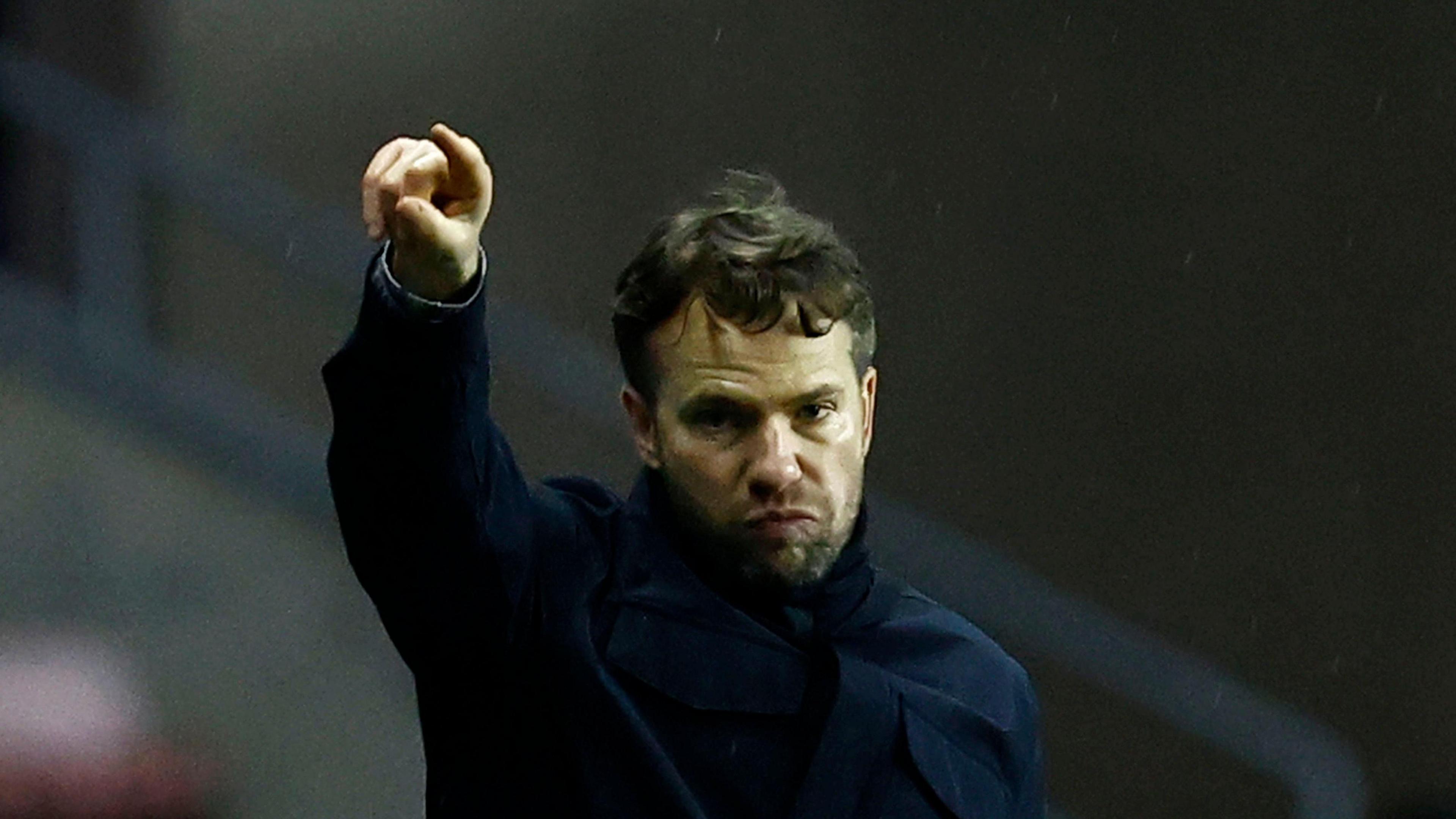 Plymouth Argyle boss Tom Cleverley pointing towards his players from the touchline with his right hand while pursing his lips together.