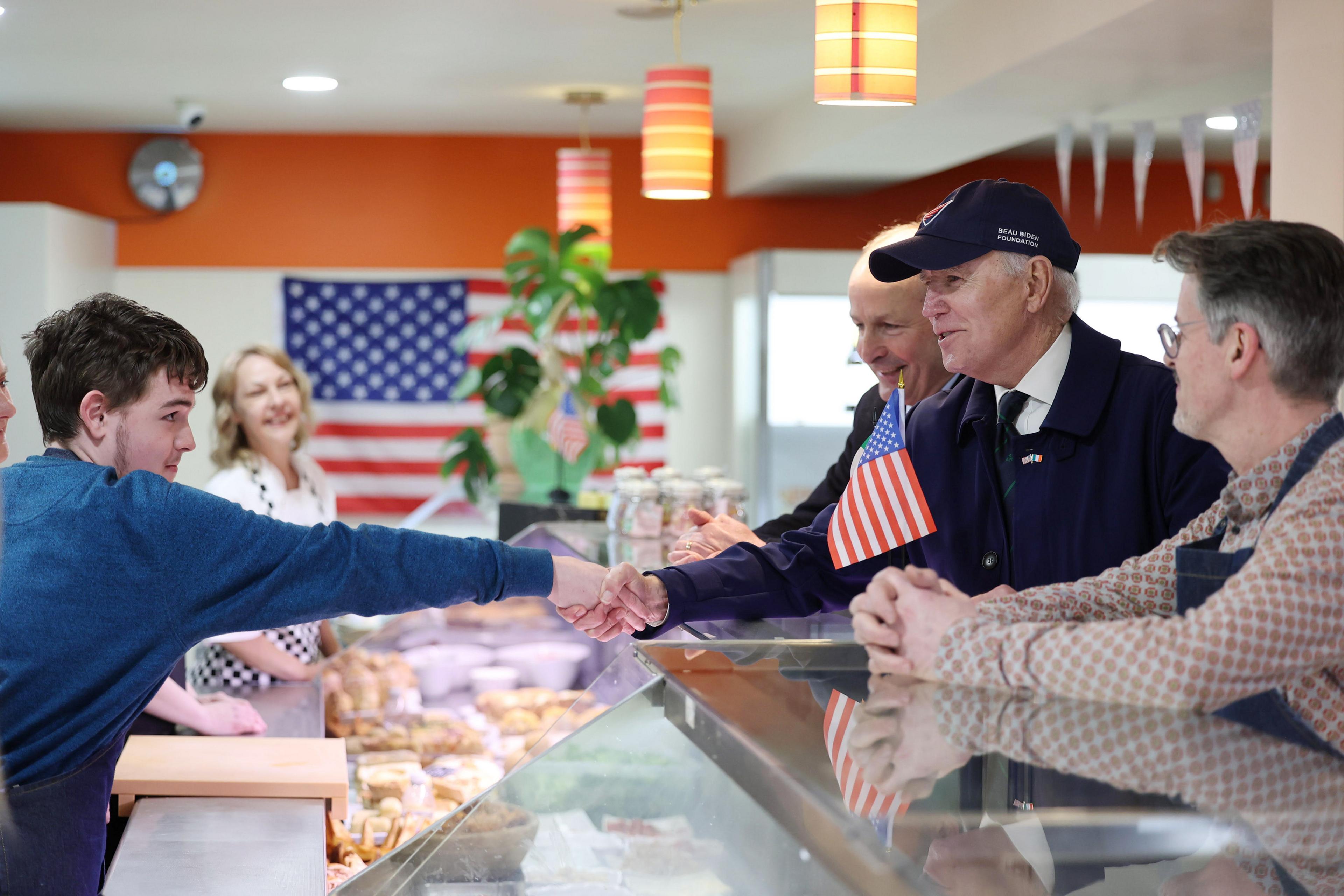 Joe Biden shakes the hand of a young man at a food shop in Dundalk