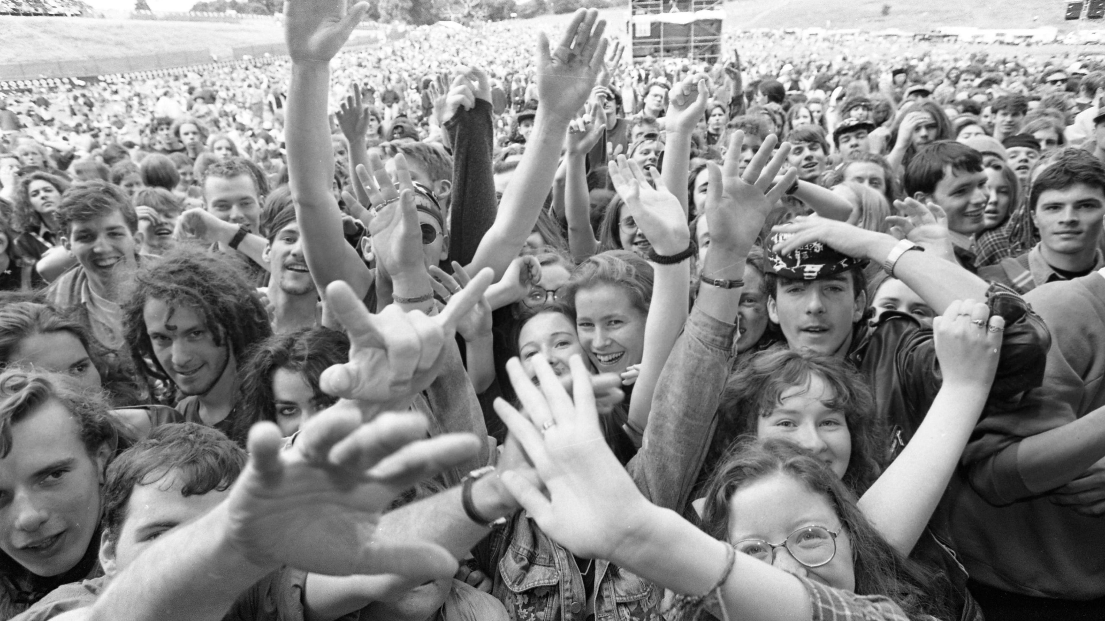 Black and white image of crowds with their hands waving at the camera at Slane Castle