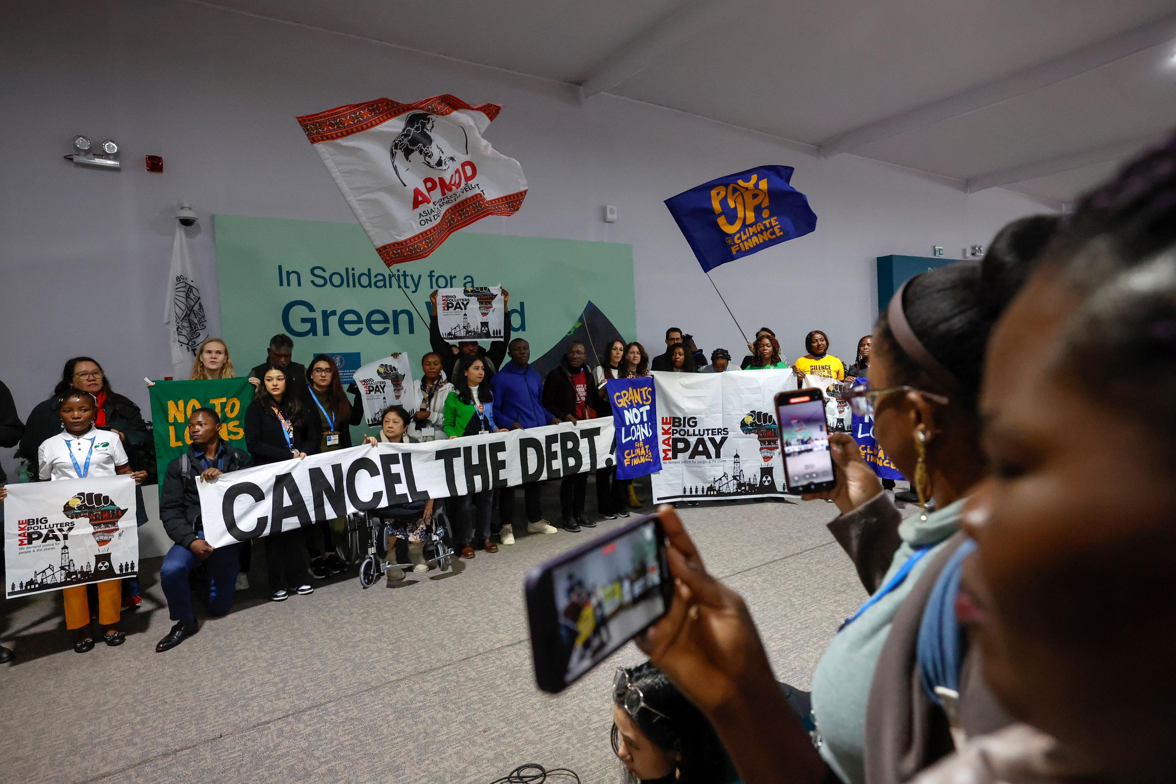 cop29 protestors holding signs asking for more to be done about climatechange being photographed by bystanders