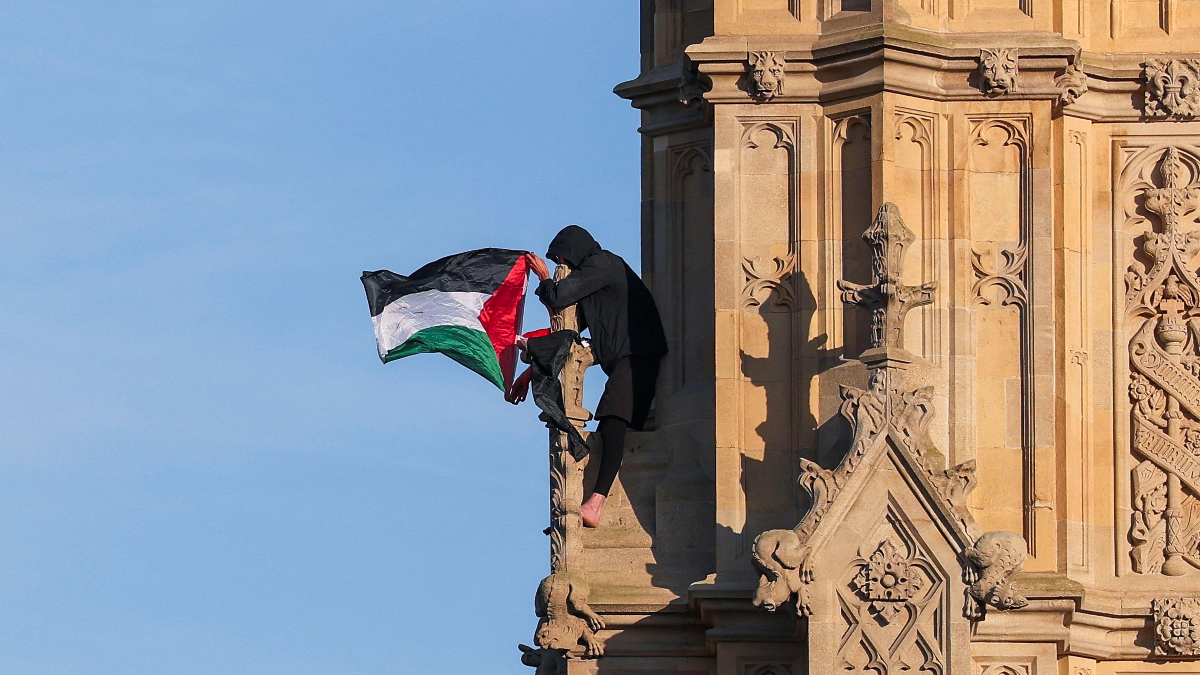 A man with a Palestinian flag sits on the Elizabeth Tower, commonly known as Big Ben.