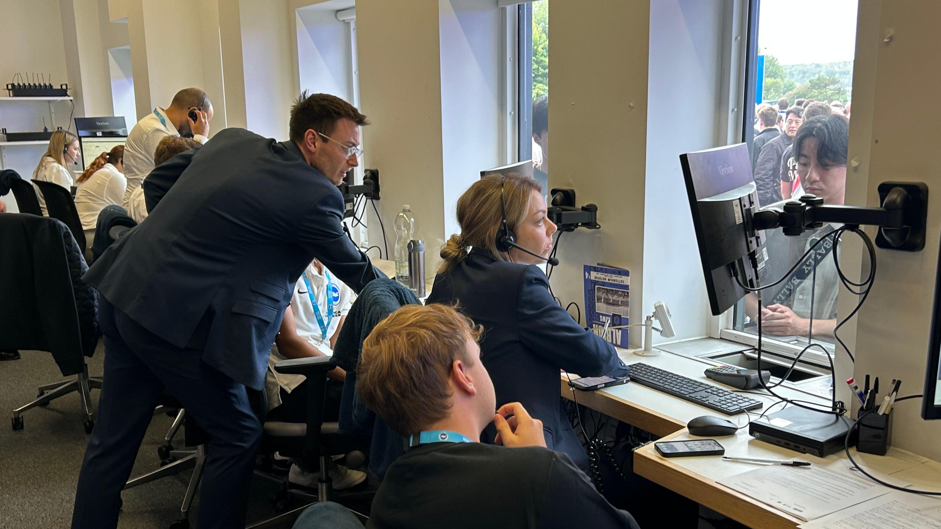 Staff sit behind desks in the Brighton ticket office at the Amex Stadium ahead of the Premier League match against Tottenham as fans queue with ticket queries