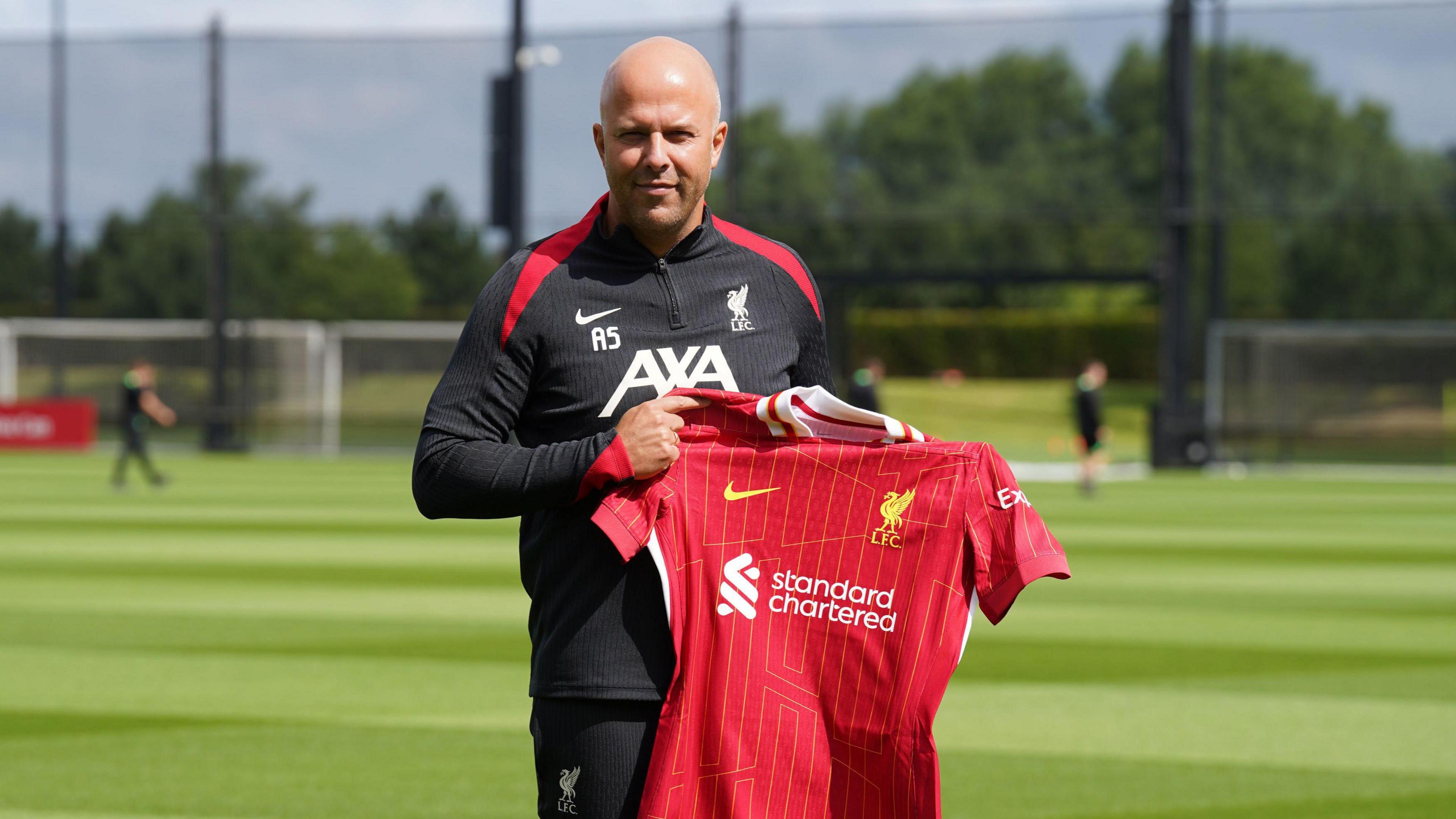 Arne Slot holding up a Liverpool shirt