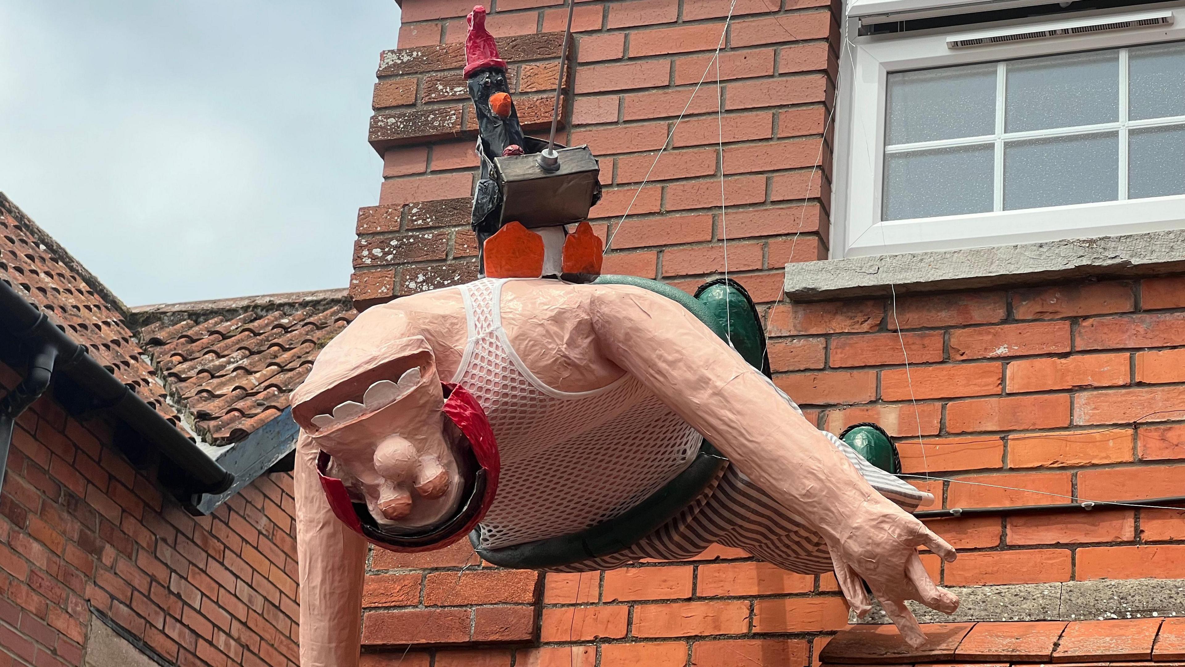 A scarecrow of Wallace and Feathers McGraw from Wallace and Gromit dangles from a property