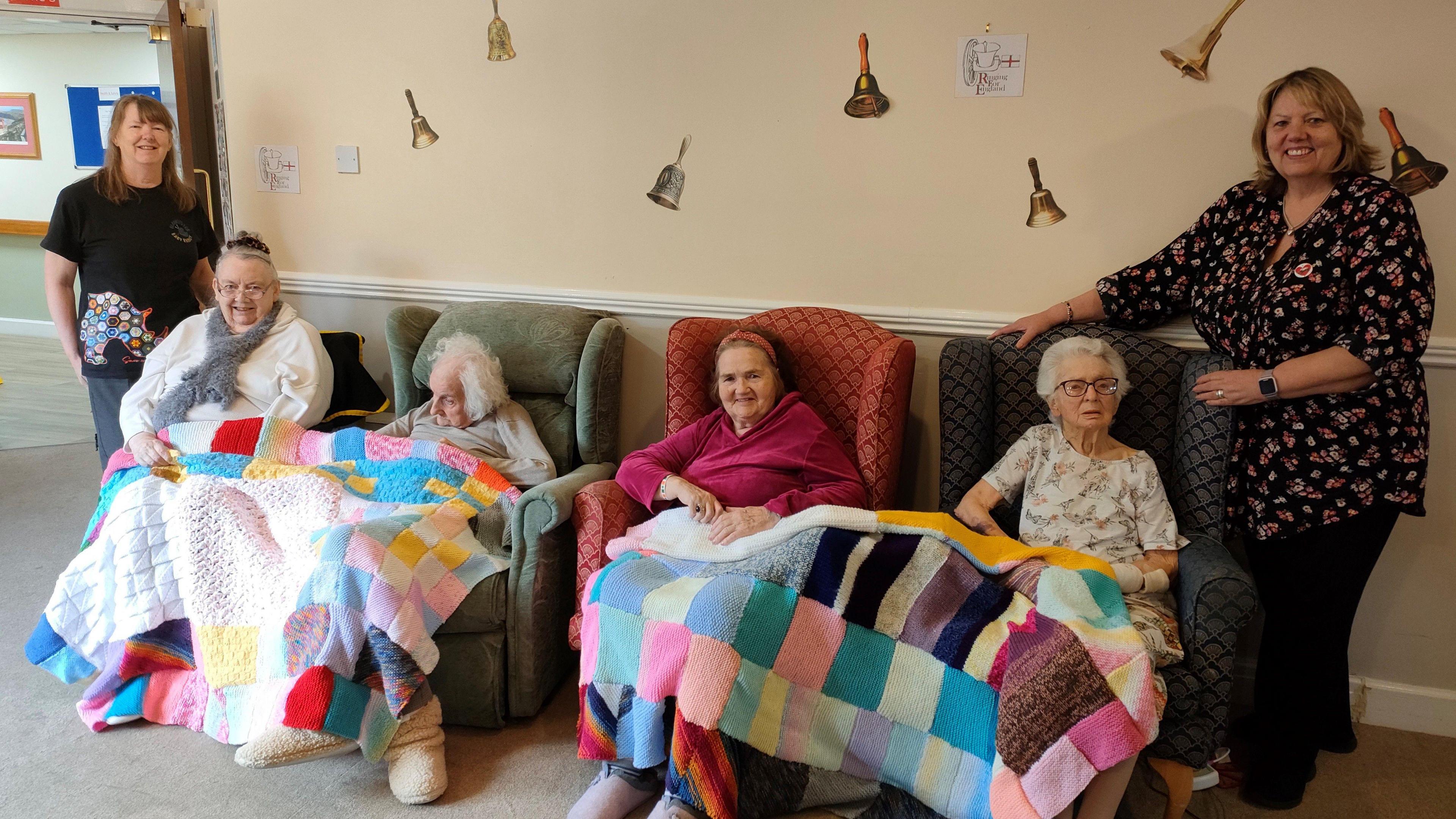 Liz Conroy, from Blankets For Baby Rhinos, with Hazelgrove Court Care Home residents Joyce Wooffindin, 83, Joyce Baxtrem, 94, Sheila O’Neill, 83, Betty Wood, 100, and Netta Danckwerts, also from Blankets For Baby Rhinos. The four elderly residents are sitting on armchairs with their colourful blankets spread across their knees.