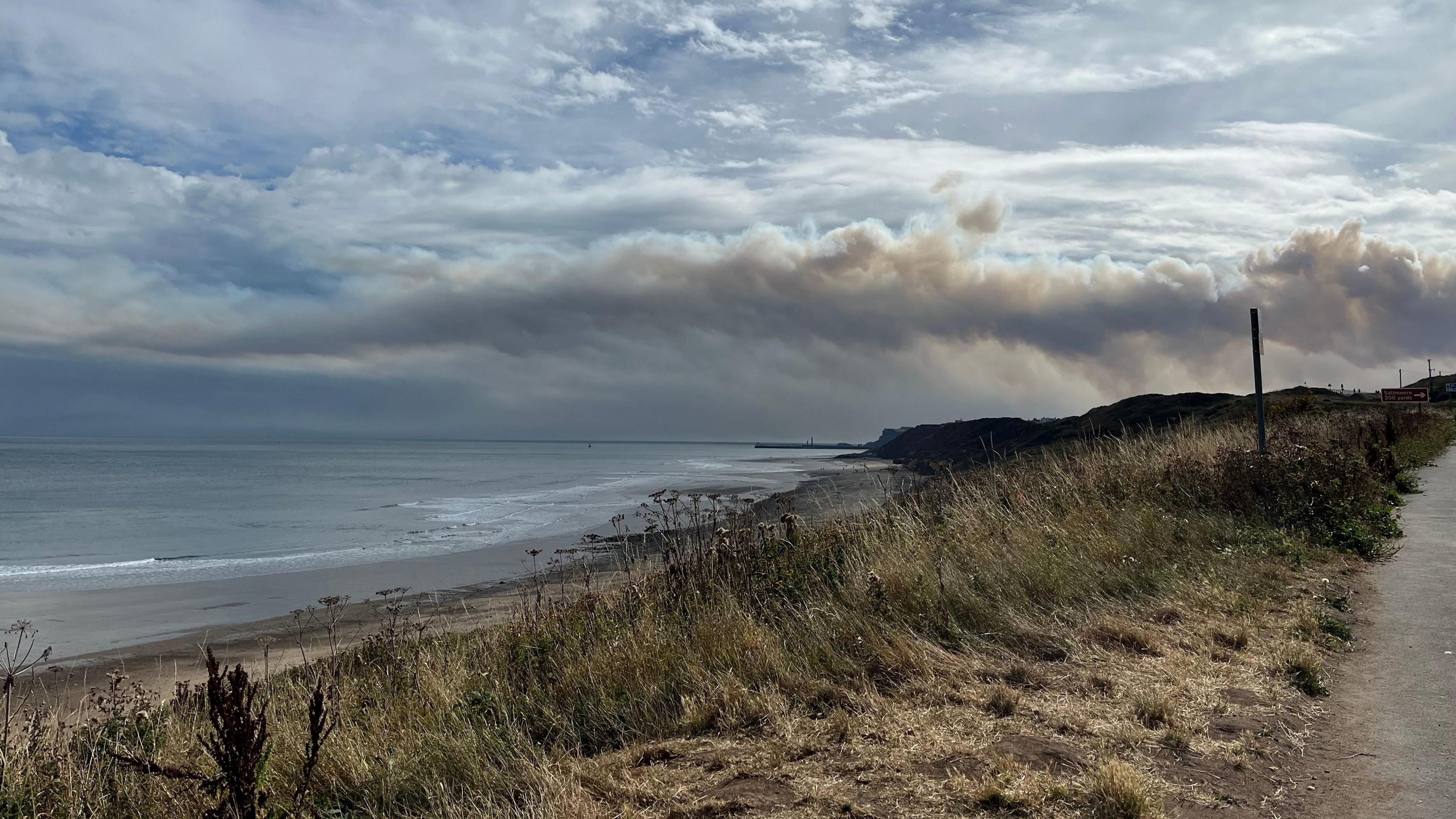 Smoke from the moorland fire visible over the coast at Sandsend near Whitby.