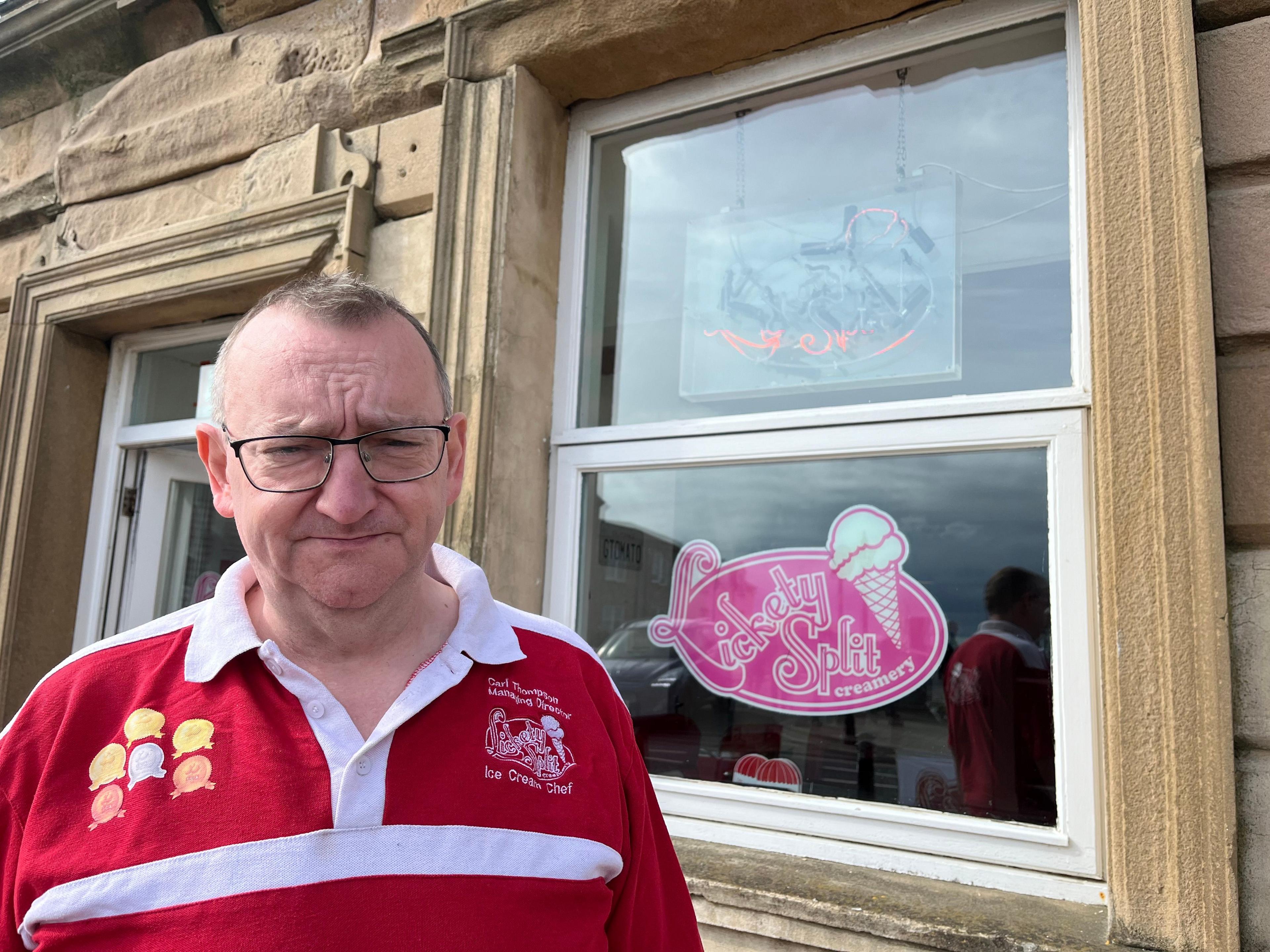 Carl Thompson outside a shop with the words Lickety Split on a poster on the wall 