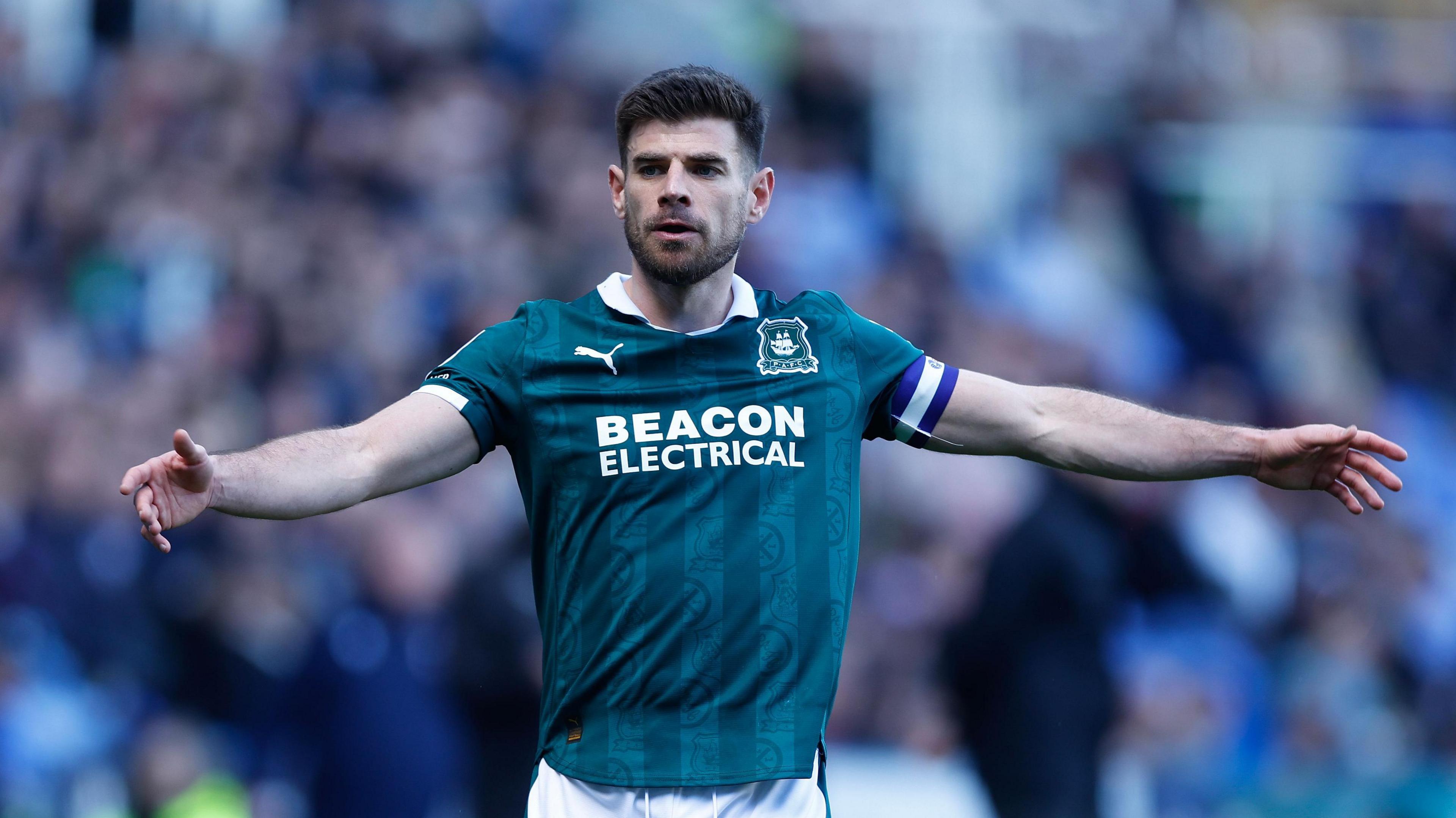 Plymouth Argyle captain Joe Edwards with his arms out wide gesticulating to his teammates.