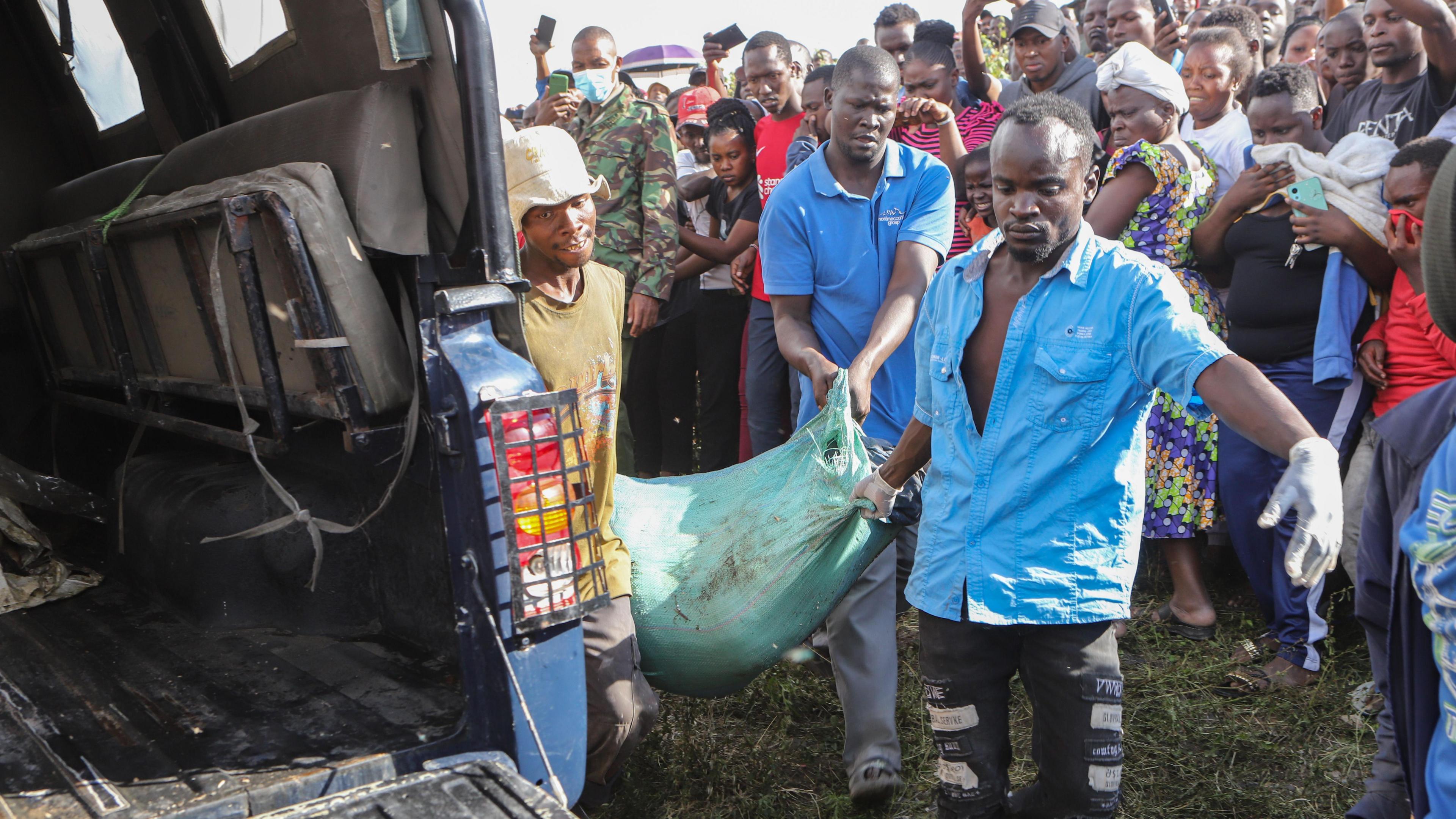 Kenyan men carrying a bag containing dismembered body parts in Nairobi, carrying to the back of a jeep